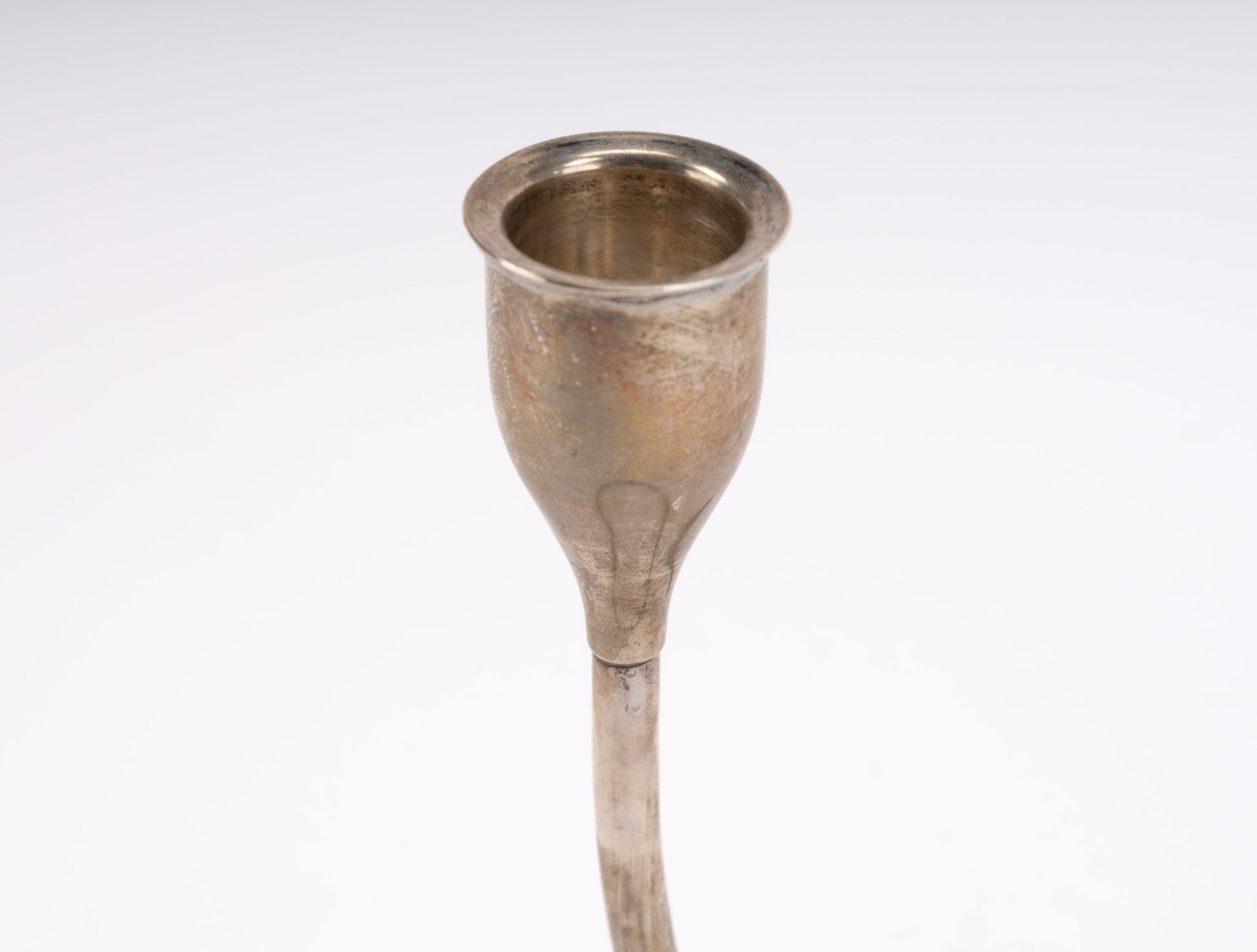 Close-up of mid-century sterling silver candlestick cup with smooth finish and plastic tip detail on white background