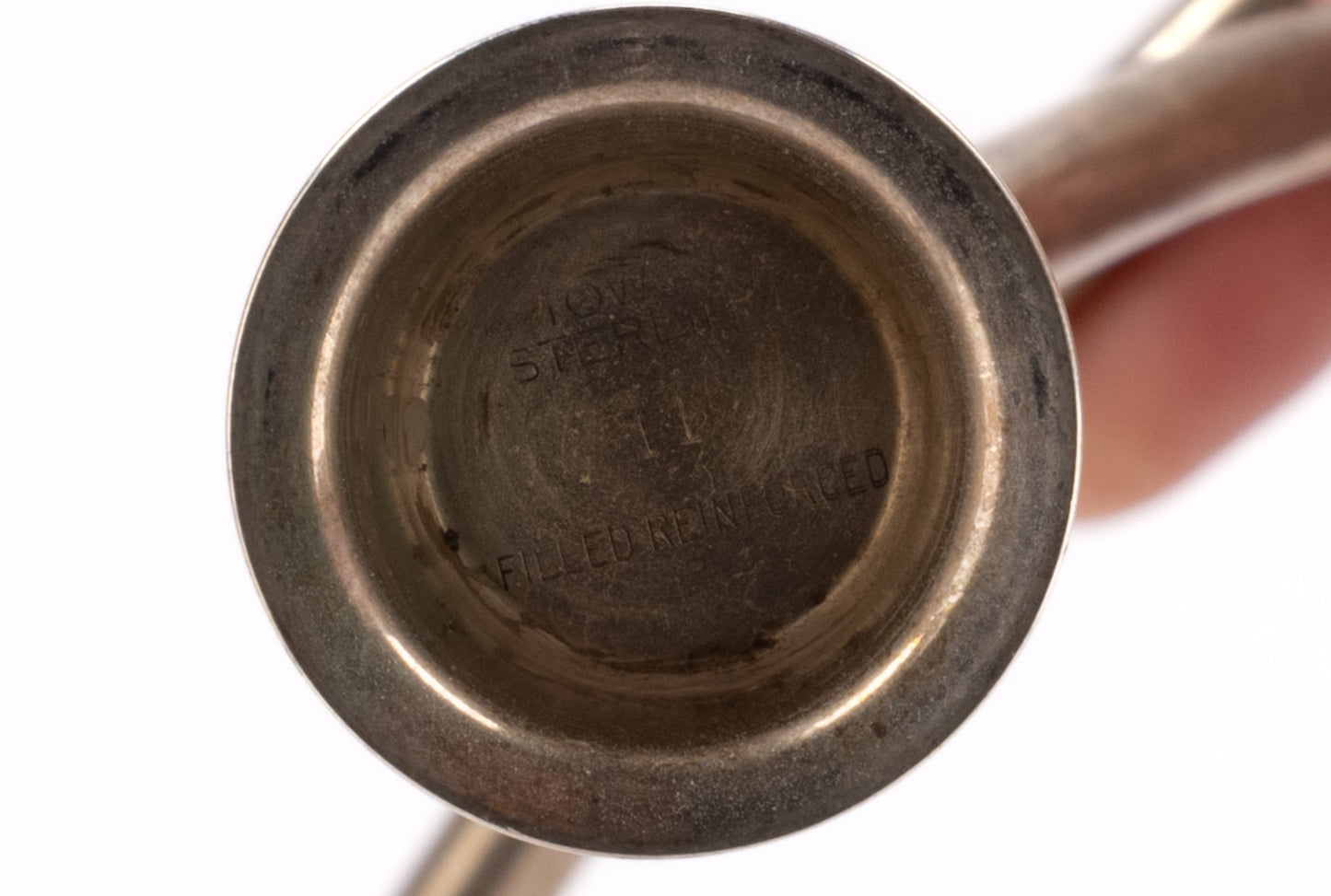 Close-up of bottom base of Marion Anderson sterling silver candlestick with engraved maker's mark on white background