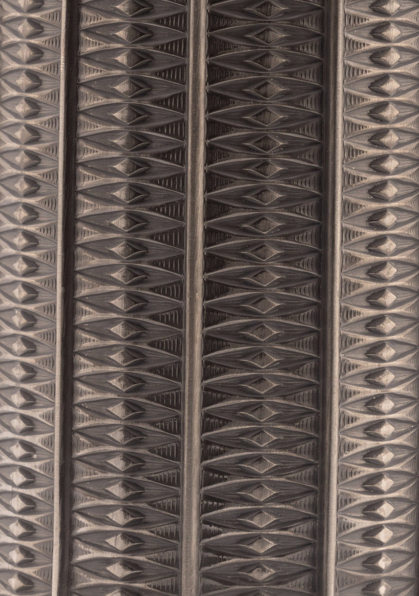Close-up of cylindrical Mastad pewter vase with engraved rows of small diamond-shaped column patterns
