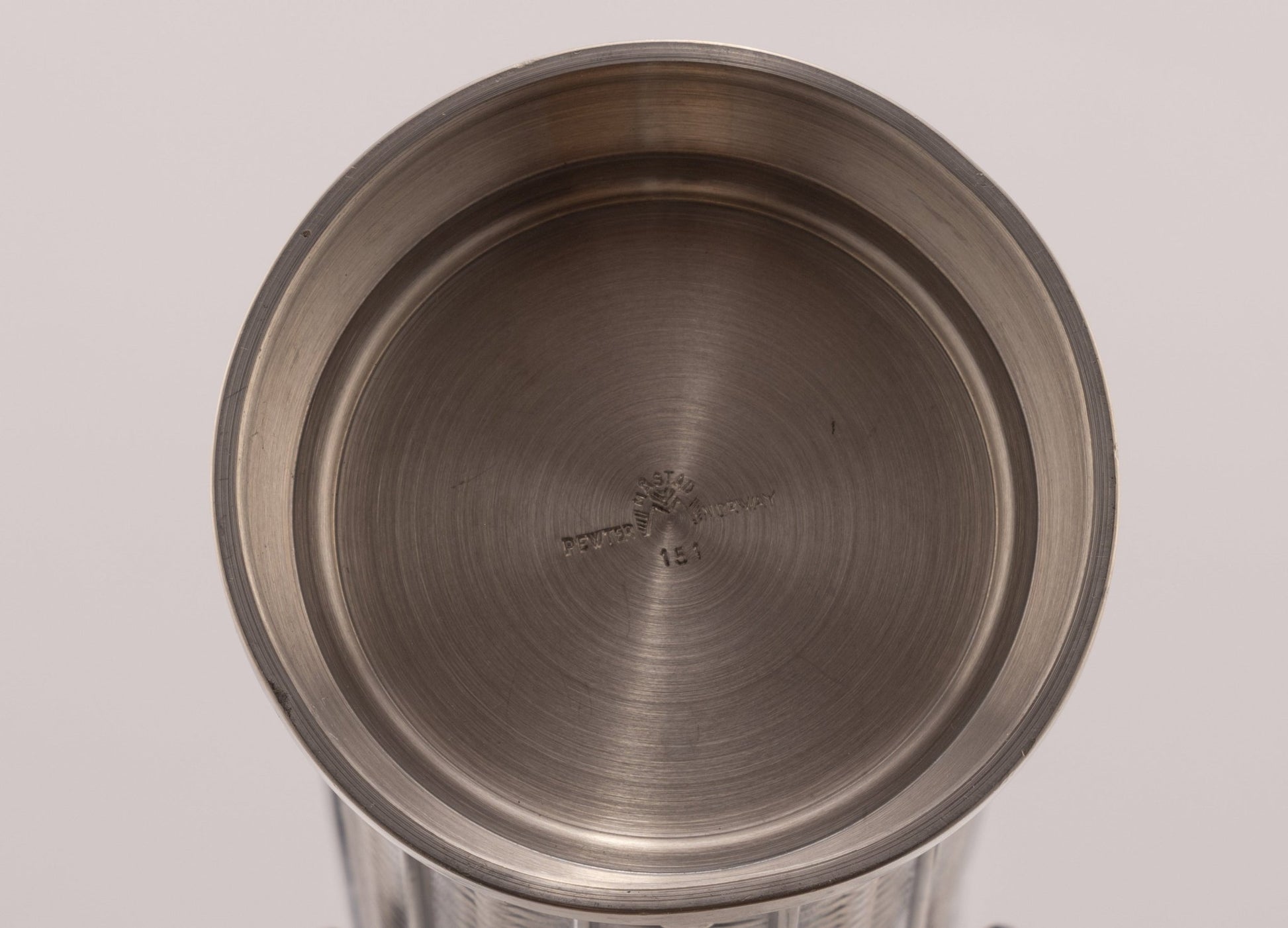 Top view of cylindrical Mastad pewter vase with engraved diamond-shaped column pattern and maker's mark on bottom
