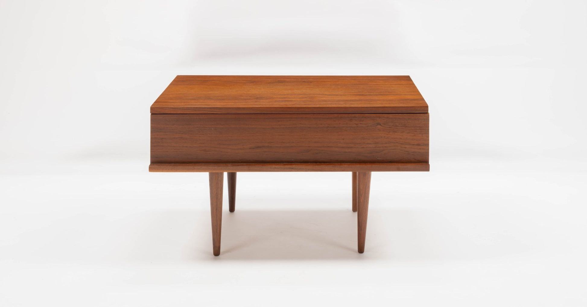 Mid-century modern walnut side table by Mel Smilow with single drawer and tapered legs on white background.