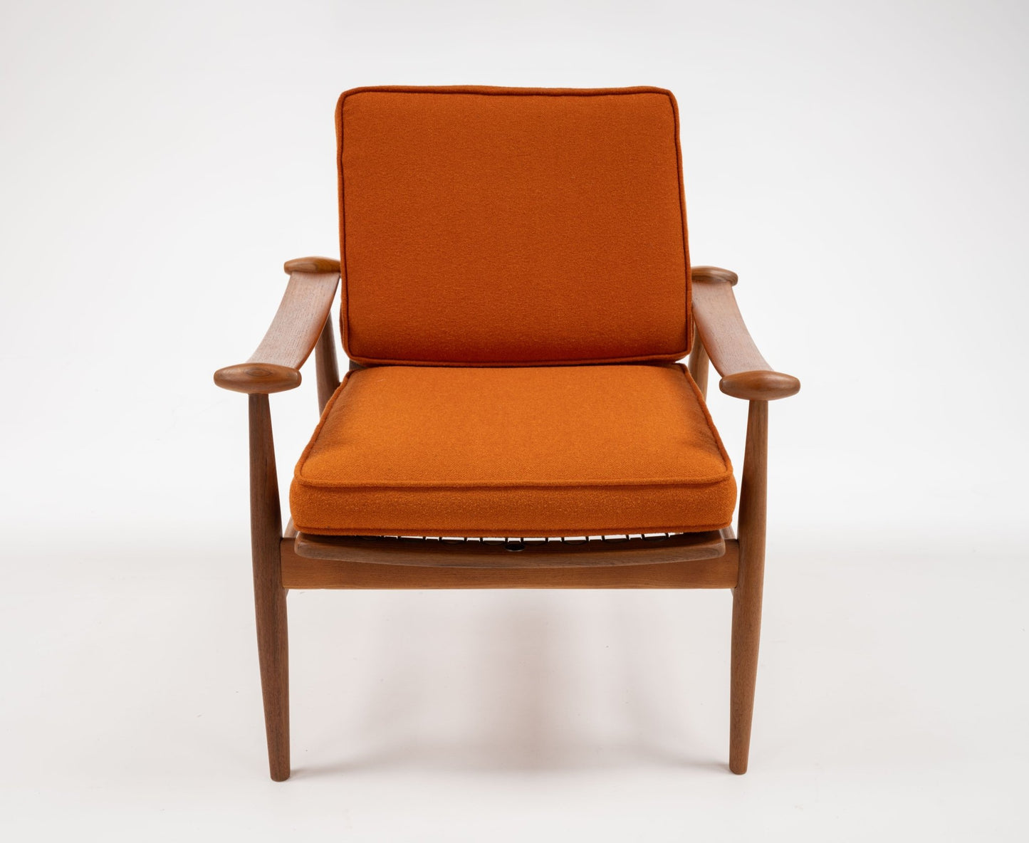 Mid-century modern teak armchair with sculpted spade-shaped arms and burnt orange cushions on white background