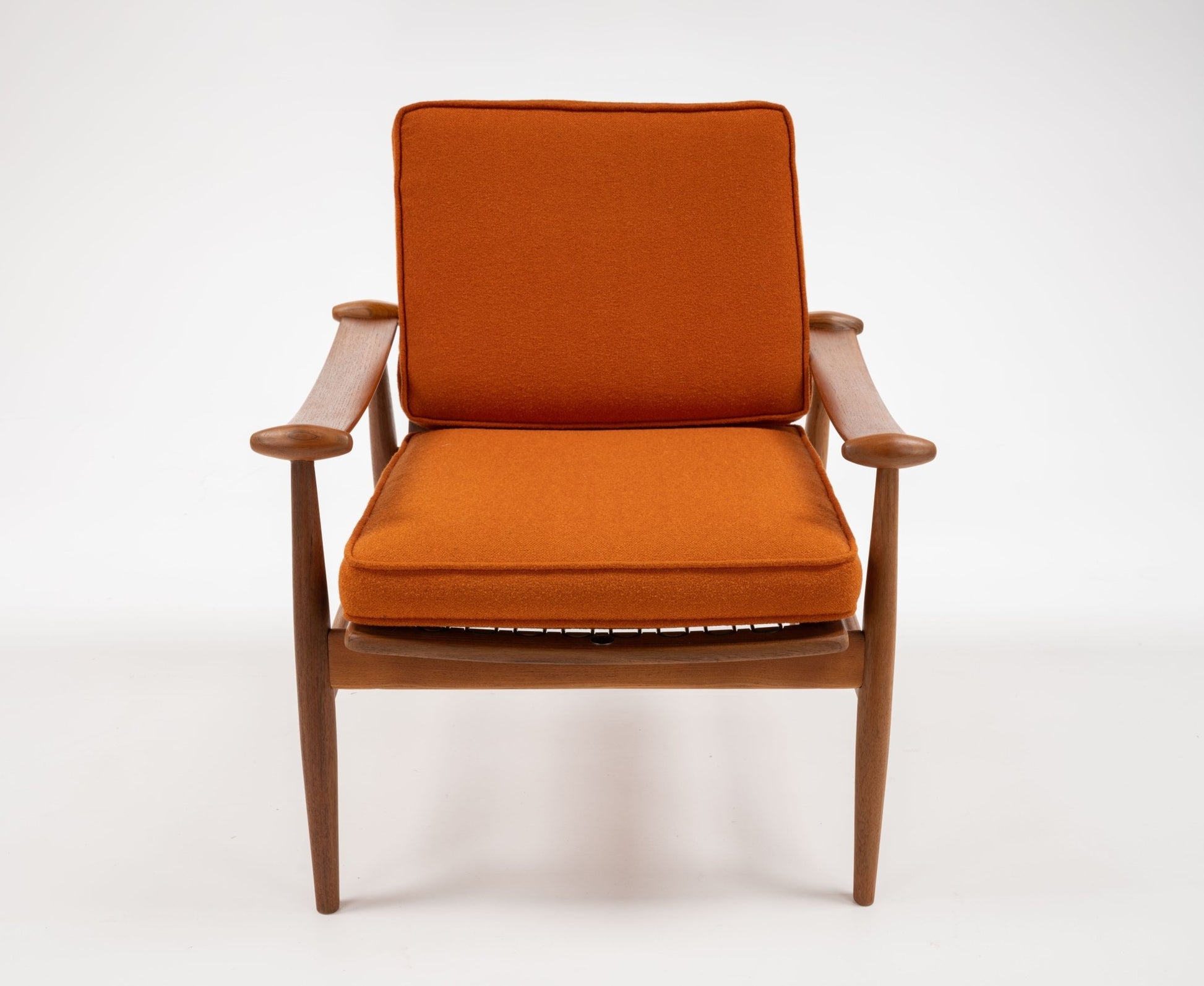 Mid-century modern teak armchair with sculpted spade-shaped arms and burnt orange cushions on white background