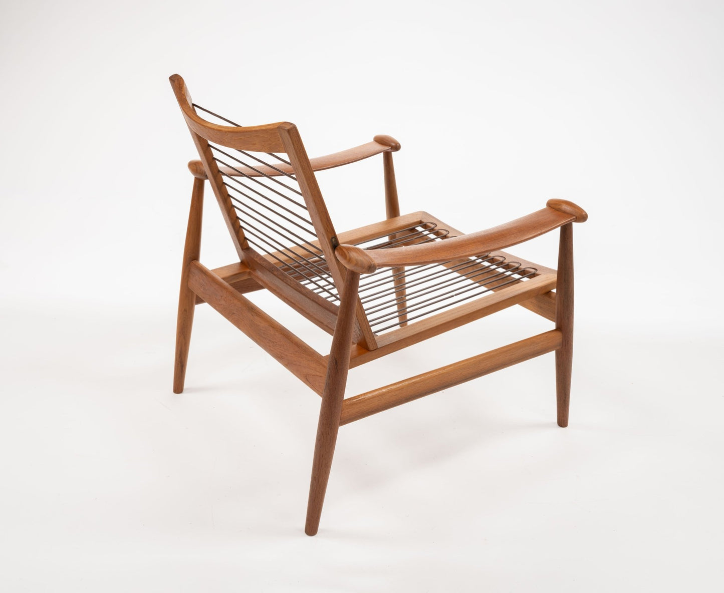 Mid-century modern teak armchair with spade-shaped arms and woven backrest showcasing Danish design.
