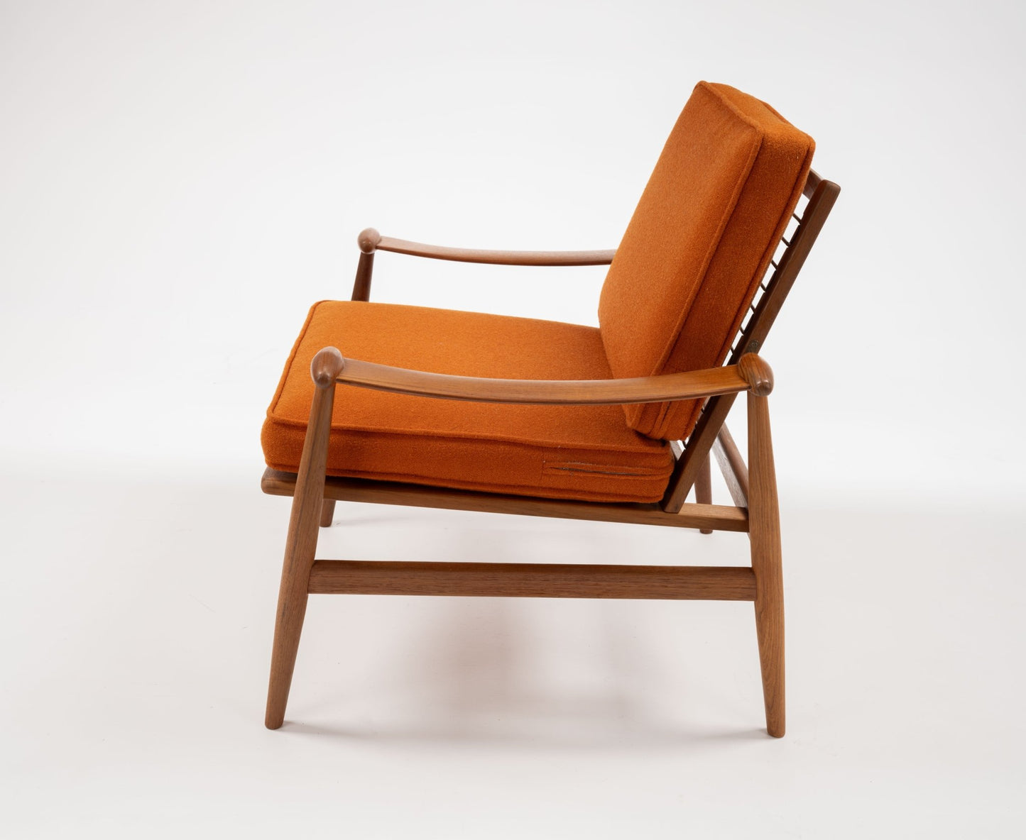 Mid-century modern Finn Juhl Model 133 Spade Armchair with teak frame and burnt orange cushions on white background