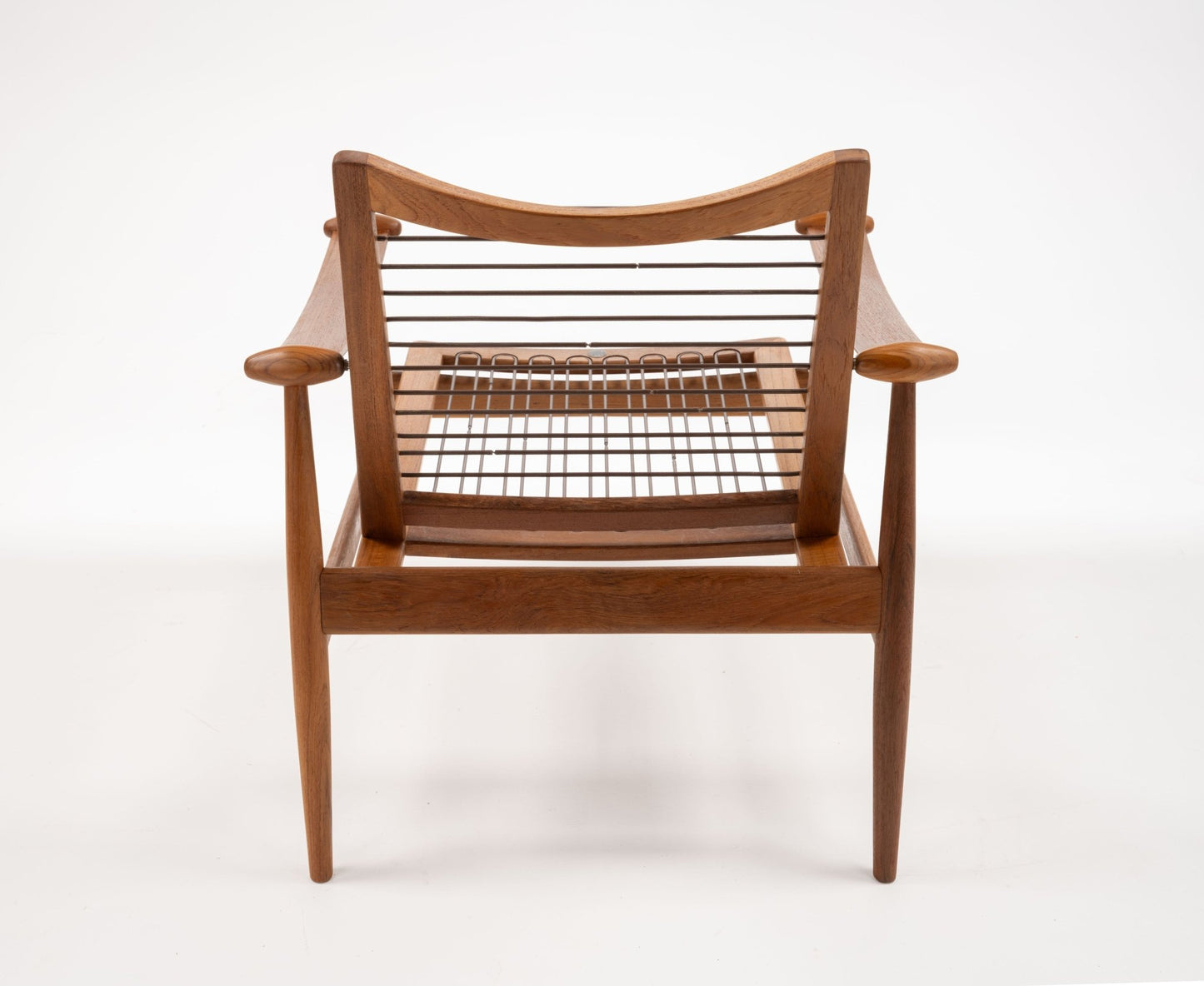 Mid-century modern solid teak Spade Armchair by Finn Juhl with sculpted armrests and open woven seat viewed from front.