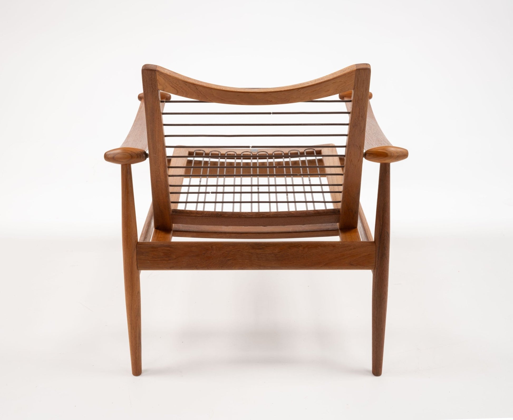Mid-century modern solid teak Spade Armchair by Finn Juhl with sculpted armrests and open woven seat viewed from front.