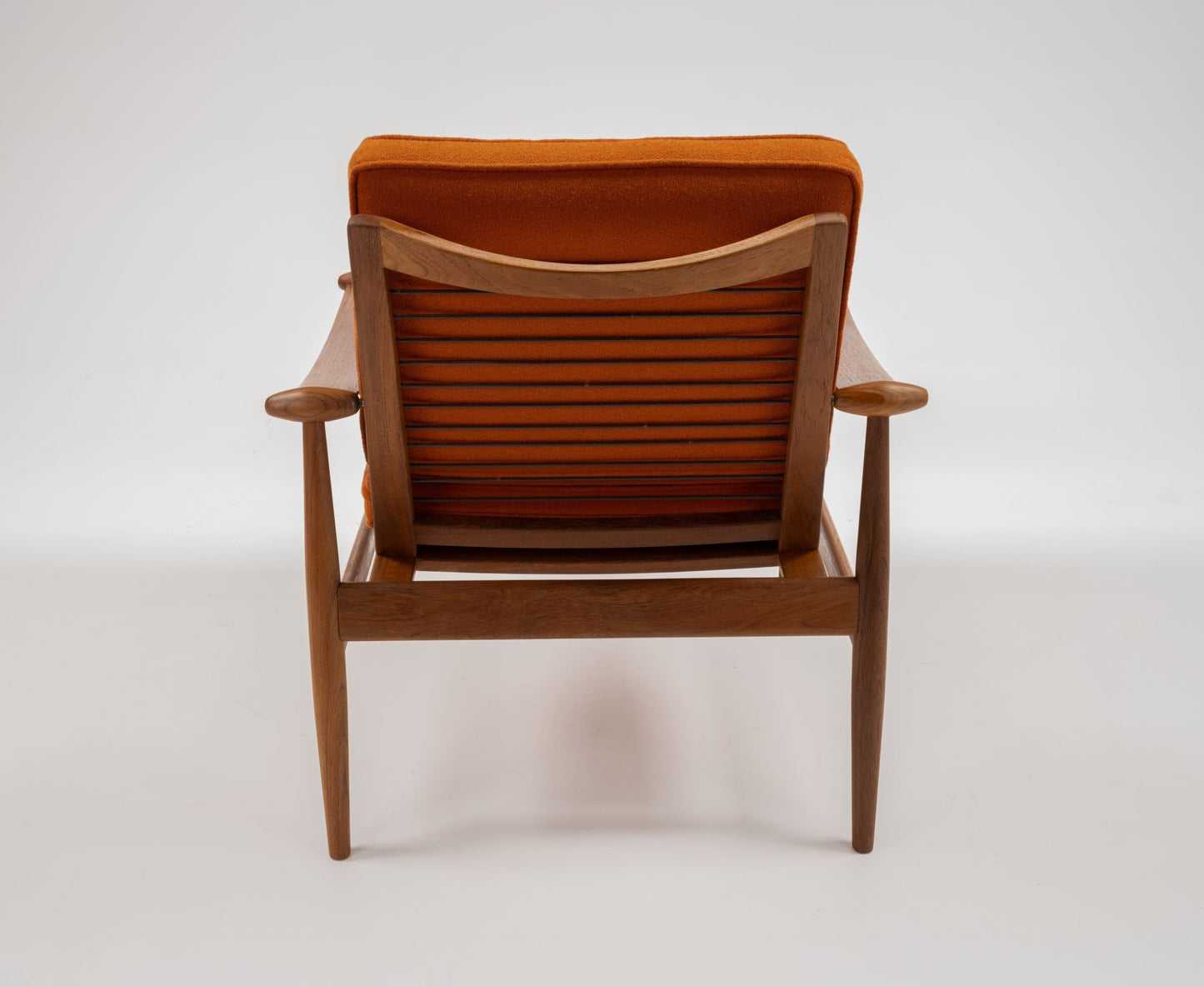 Rear view of mid-century modern Model 133 Spade Armchair by Finn Juhl with teak frame and burnt orange upholstery