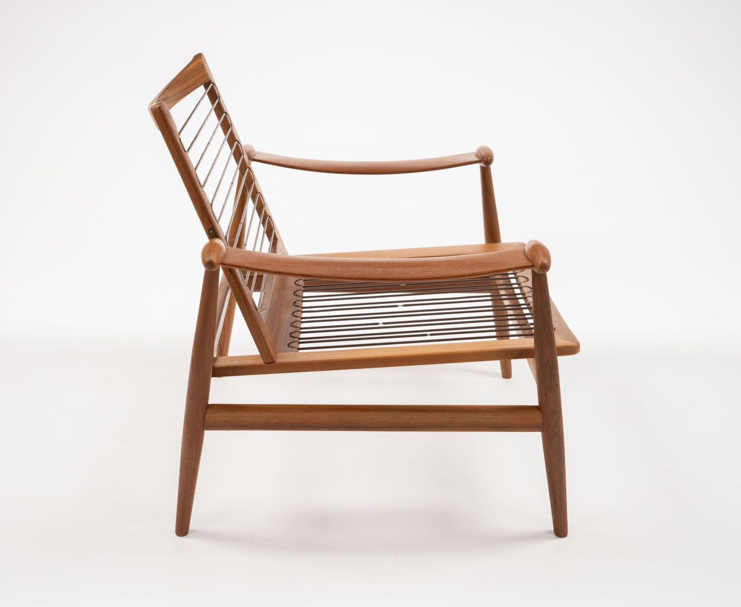 Mid-century modern teak Spade Armchair by Finn Juhl with curved arms and woven seat and backrest on white background.