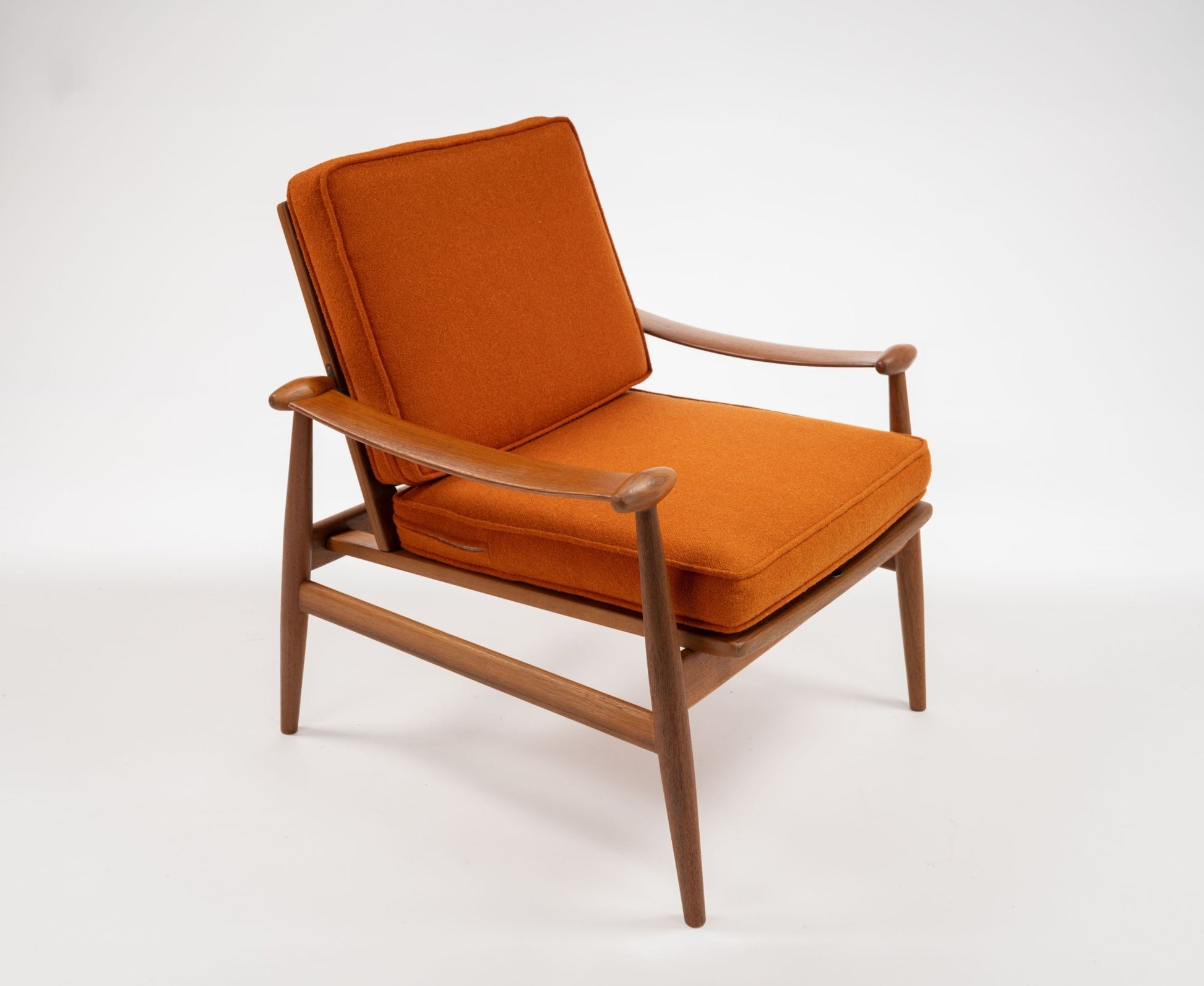 Mid-century modern teak spade armchair with curved arms and burnt orange cushions on white background