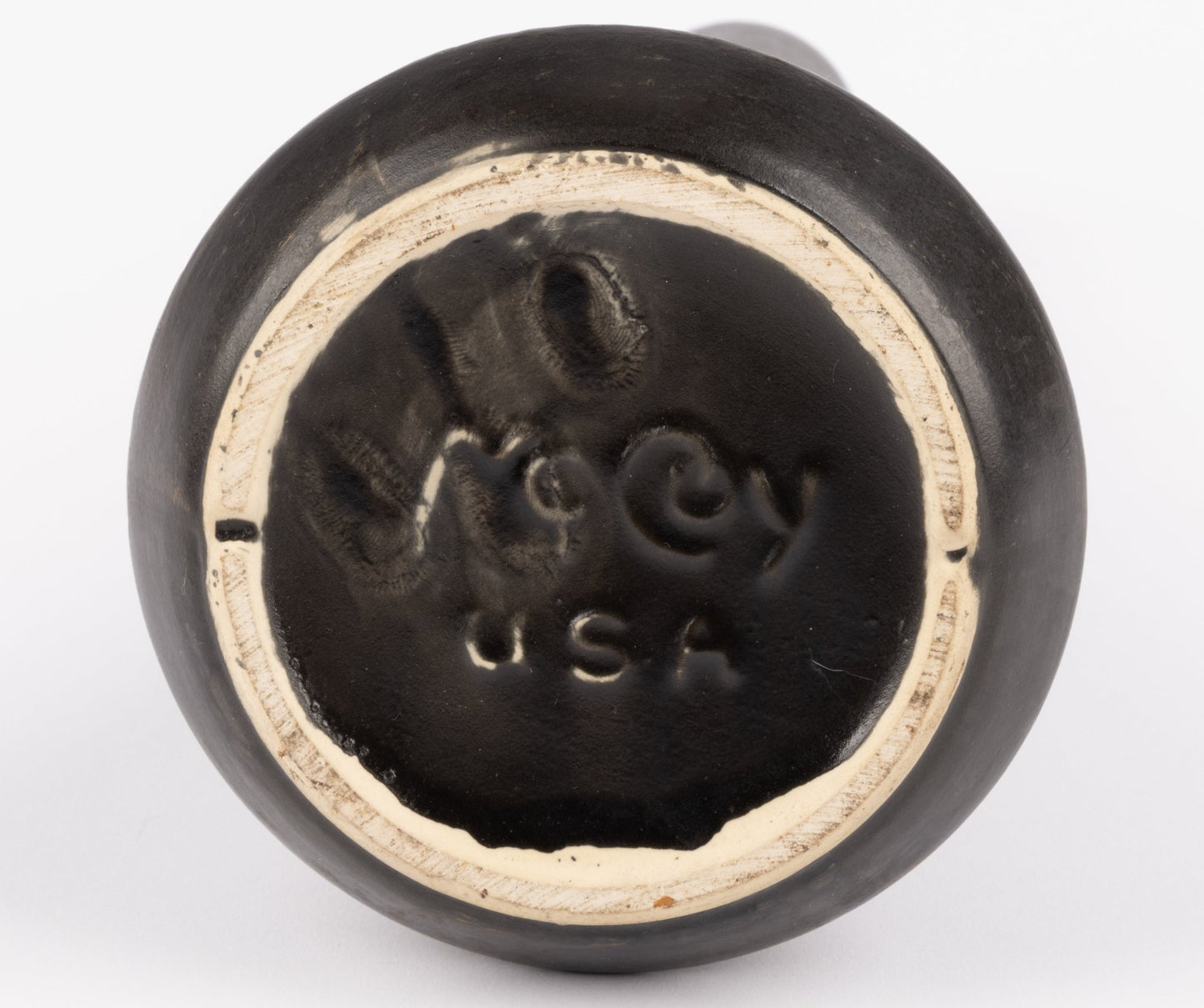 Bottom view of Nelson McCoy pottery vase showing black glaze and embossed maker mark USA on unglazed ceramic base
