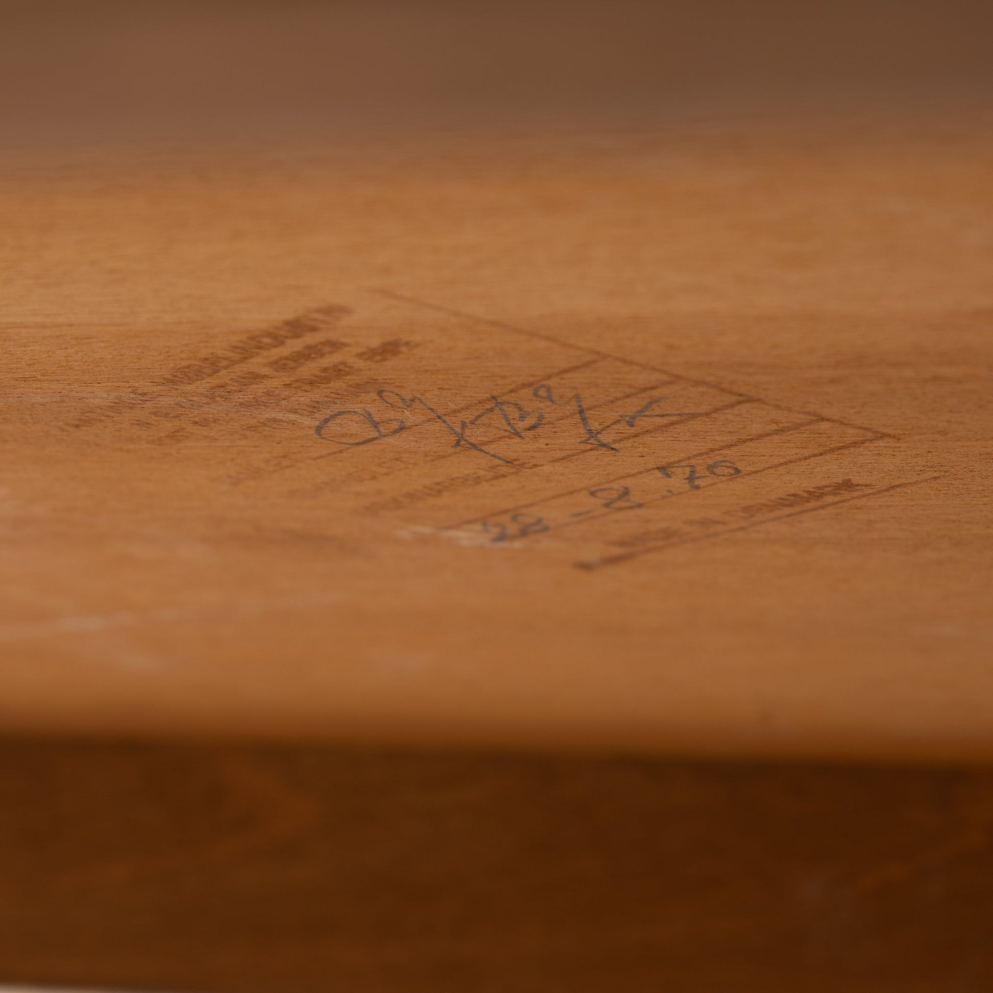 Niels Erik & Glasdam Jensen Teak Expanding Bar Cart detail showing close-up of its warm teak wood surface with handwritten vintage markings, highlighting authentic mid century modern craftsmanship.