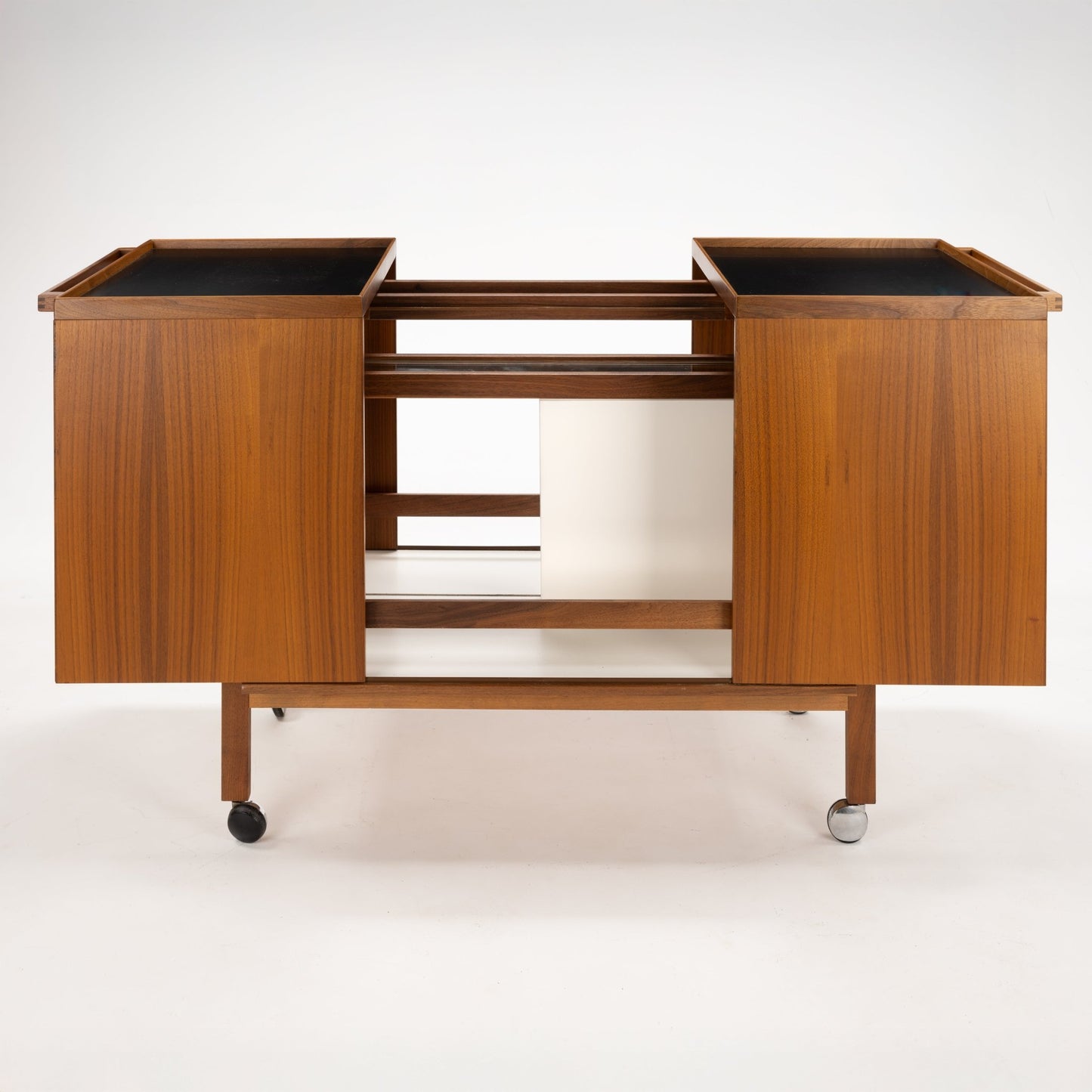 Niels Erik & Glasdam Jensen Teak Expanding Bar Cart with rich teak veneer panels, clean-lined design, expandable trays featuring dark surfaces, and durable caster wheels for versatile mid century modern storage and serving.