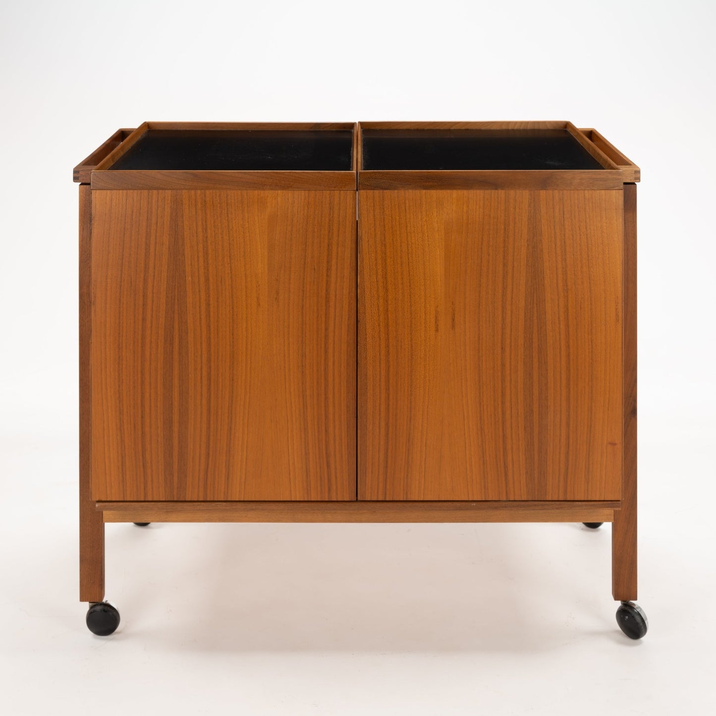 Niels Erik & Glasdam Jensen Teak Expanding Bar Cart showcasing a warm teak finish, clean rectangular panels, smooth black trays, and caster wheels for vintage Danish mid century modern storage and serving.