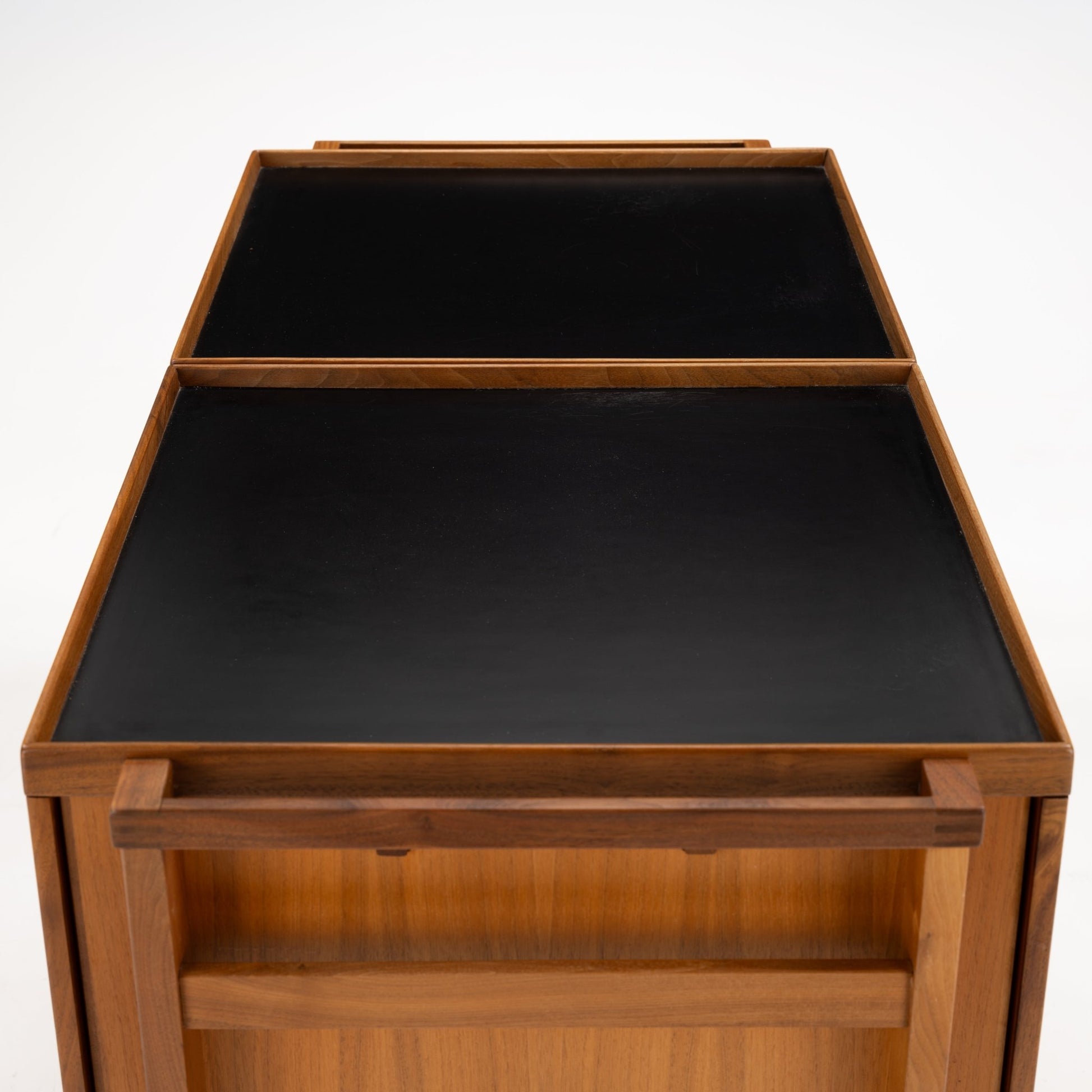 Niels Erik & Glasdam Jensen Teak Expanding Bar Cart with smooth black tray surfaces, warm teak frame, a sturdy handle, and an open shelving section, exemplifying vintage Danish mid century modern furniture.