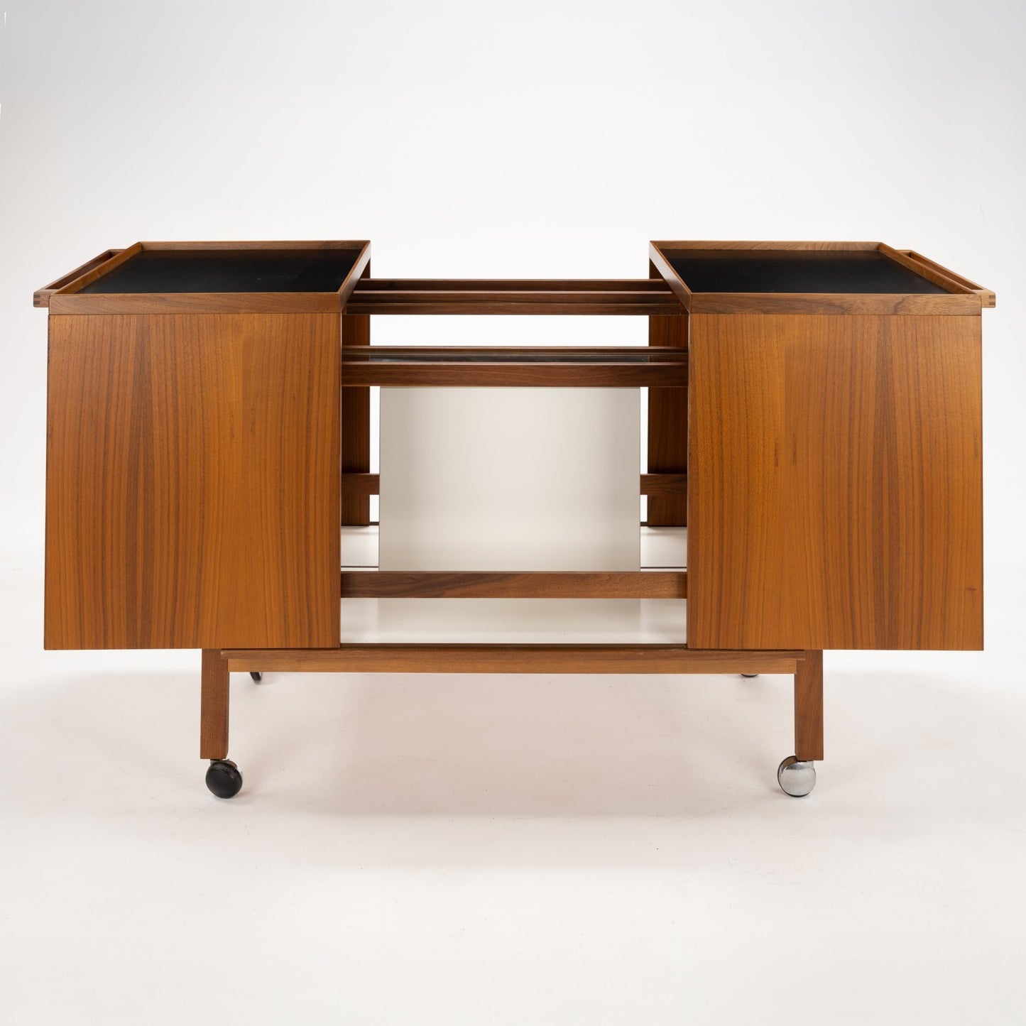 Niels Erik & Glasdam Jensen Teak Expanding Bar Cart with smooth teak panels, open middle shelving, and caster wheels combining vintage Danish storage with functional mid century modern design.