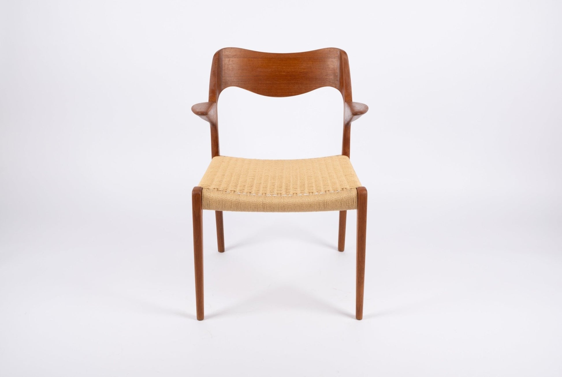 Niels Moller mid-century modern teak dining chair with sculpted backrest and woven Danish cord seat on white background.