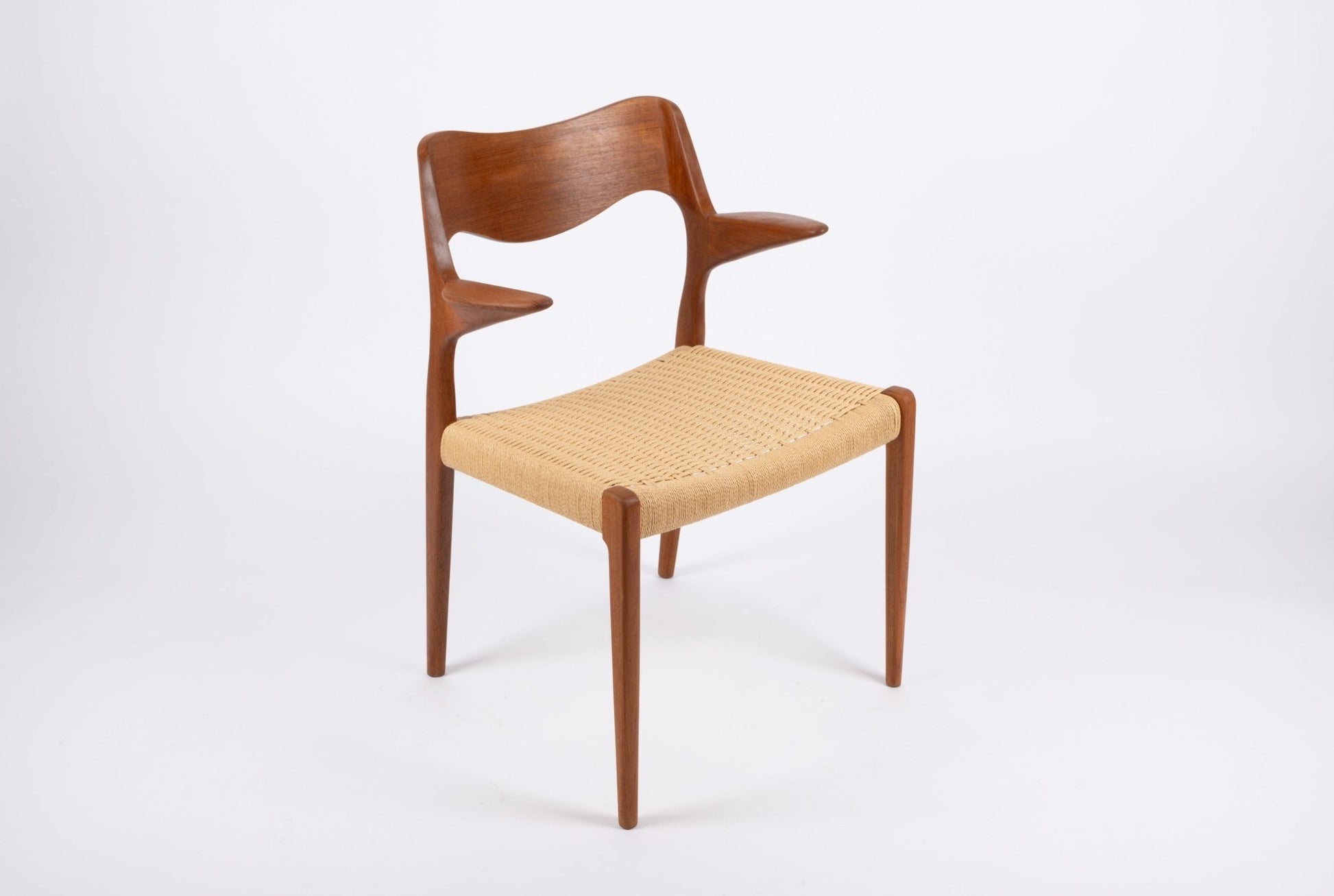 Mid-century modern Niels Moller dining chair with sculpted teak frame and woven Danish cord seat on white background