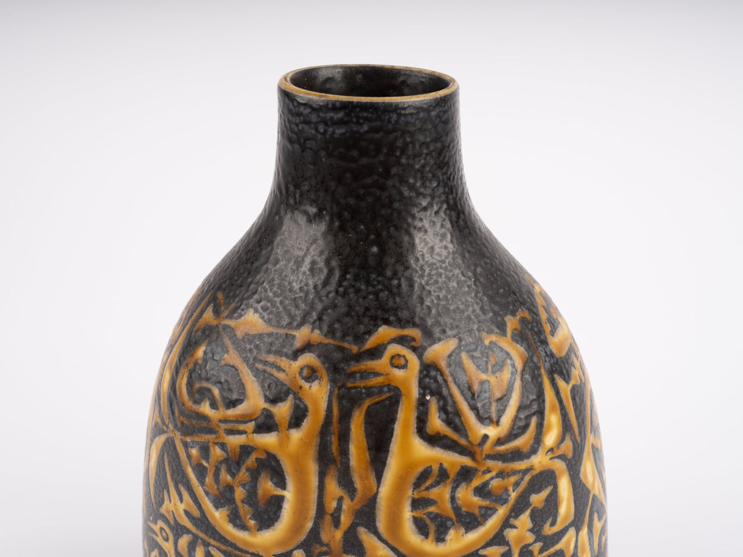 Close-up of 1960s Nils Thorsson fajance vase for Royal Copenhagen with textured black glaze and orange bird motif