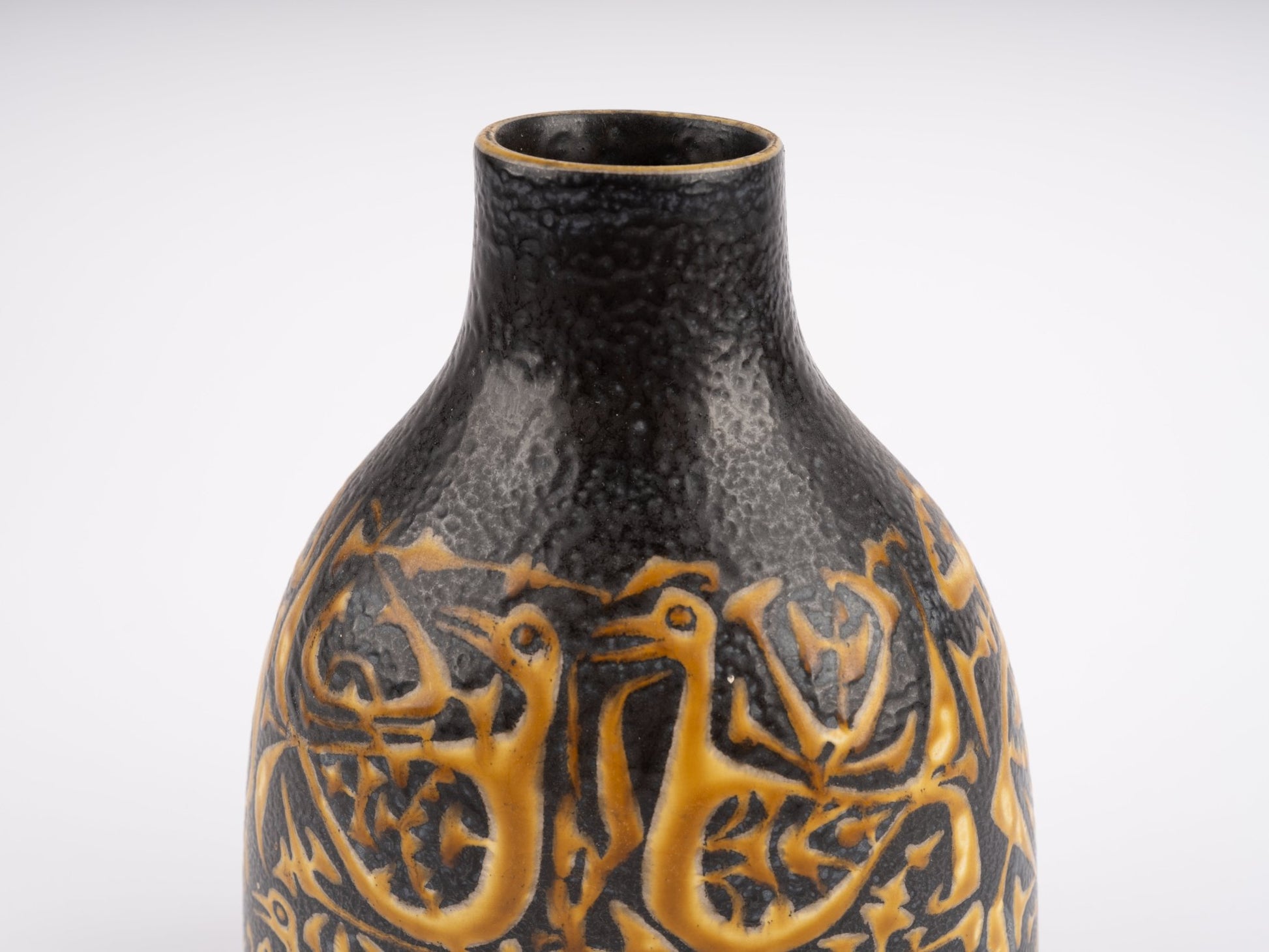 Close-up of 1960s Nils Thorsson fajance vase for Royal Copenhagen with textured black glaze and orange bird motif