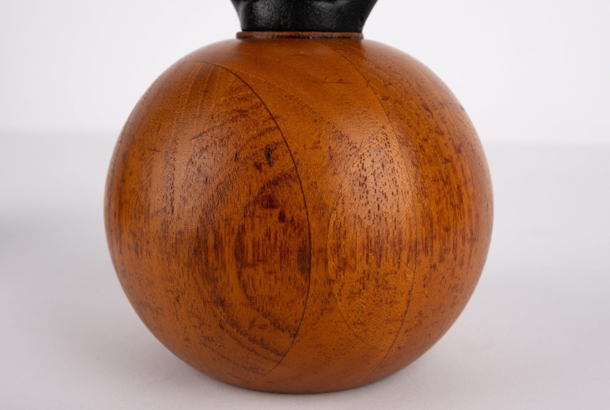 Close-up of vintage 1960s Danish salt or pepper mill with solid teak wood body and rounded black iron handle by Nissen & Jorgensen