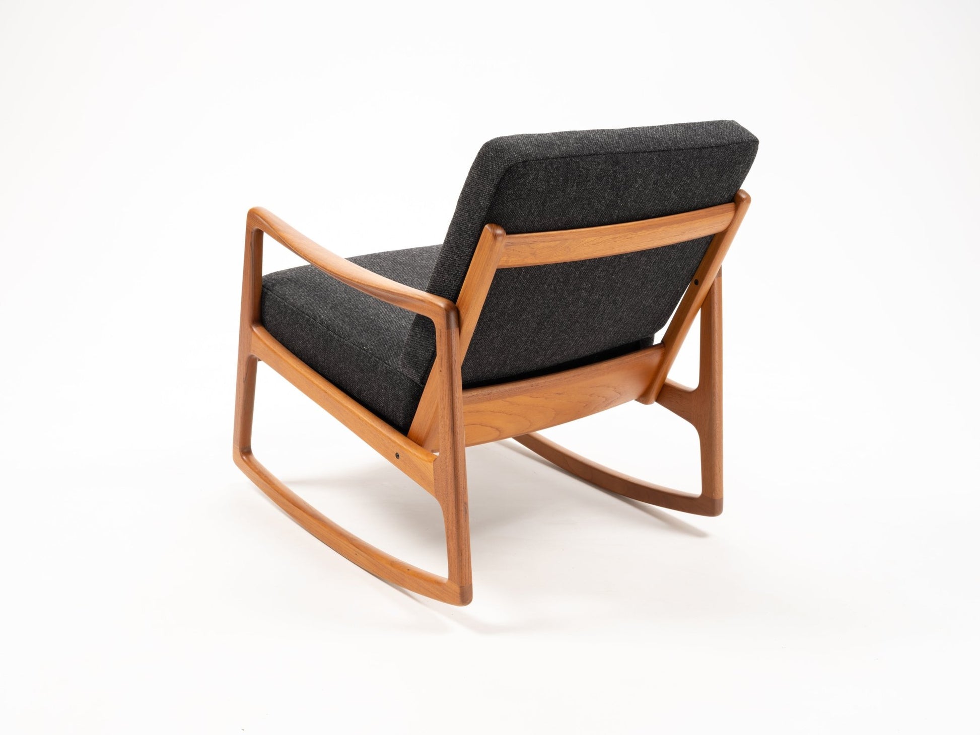Ole Wanscher teak rocking chair with sculpted armrests and dark upholstered cushions, featuring an open-back design.