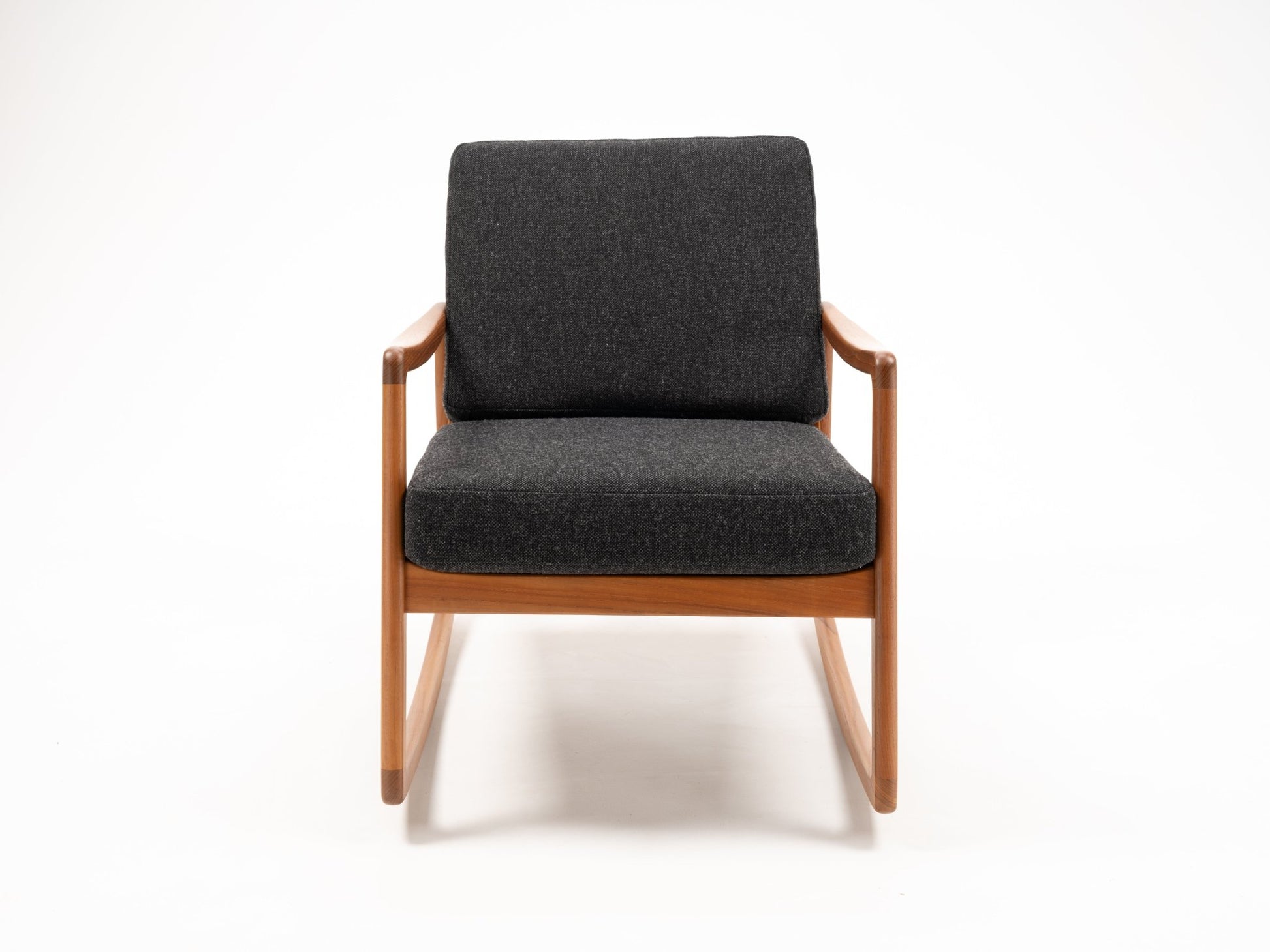 Ole Wanscher teak rocking chair with sculpted armrests and dark upholstered seat and backrest on white background