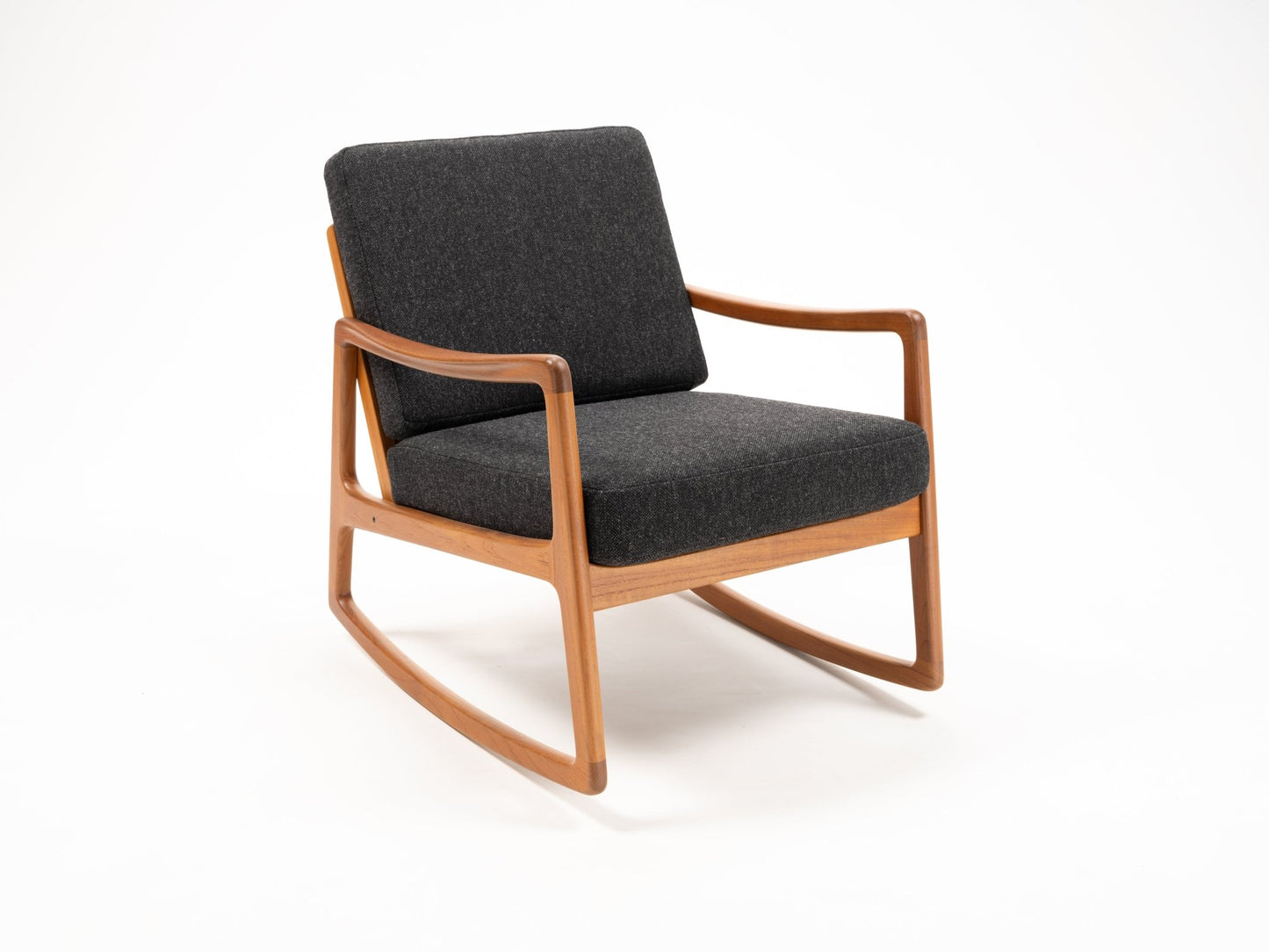 Ole Wanscher teak rocking chair with dark gray cushions and sculpted armrests on light background