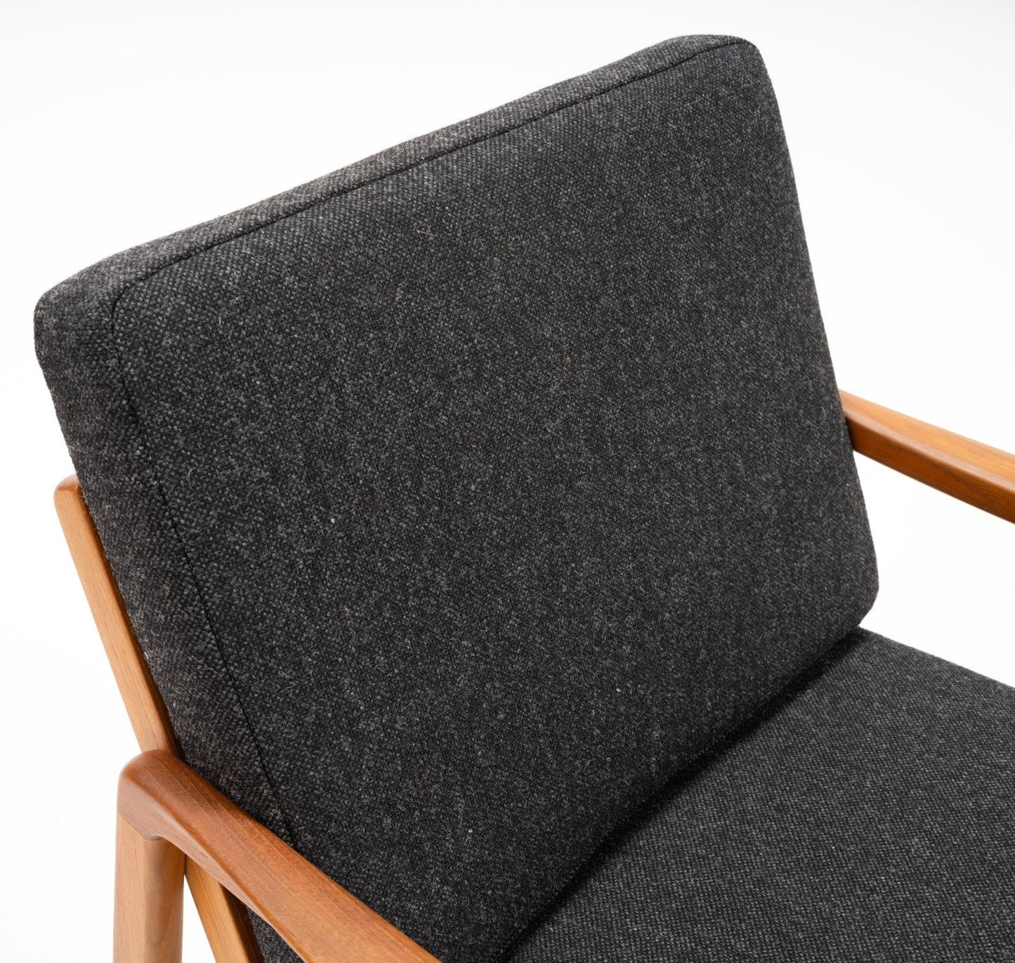 Close-up of Ole Wanscher rocking chair with solid teak frame and dark grey upholstered cushions, 1960s Danish design.