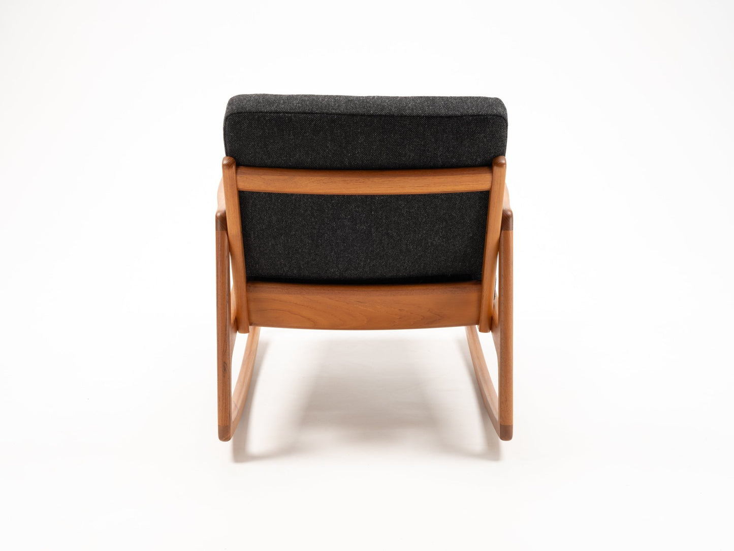 Rear view of Ole Wanscher mid-century teak rocking chair with dark upholstered cushion and sculpted armrests