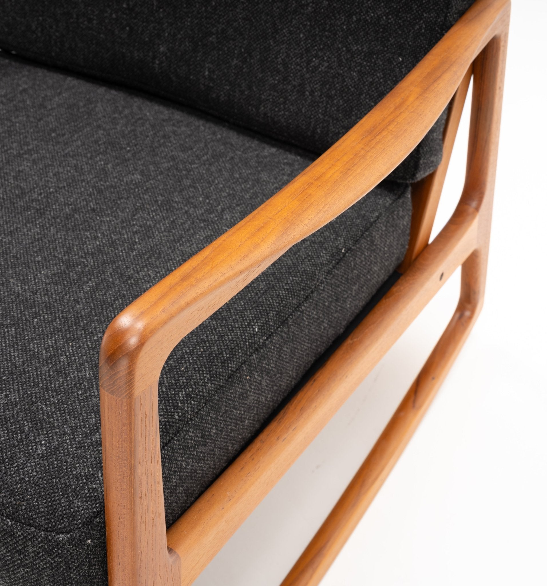 Close-up of mid-century modern Ole Wanscher teak rocking chair armrest with black upholstered cushion detail