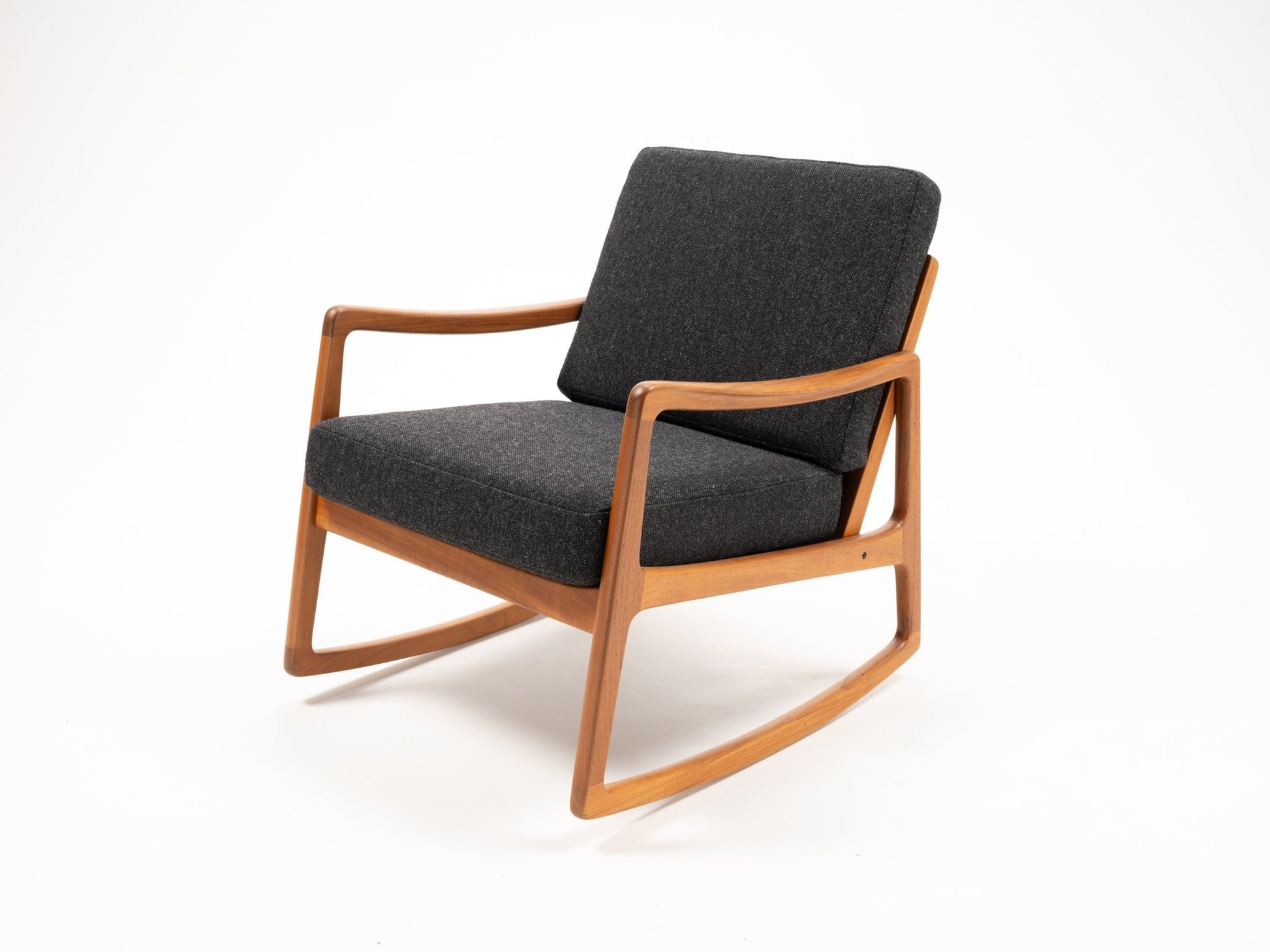 Ole Wanscher teak rocking chair with sculpted armrests and dark gray cushions, mid-century Danish design.