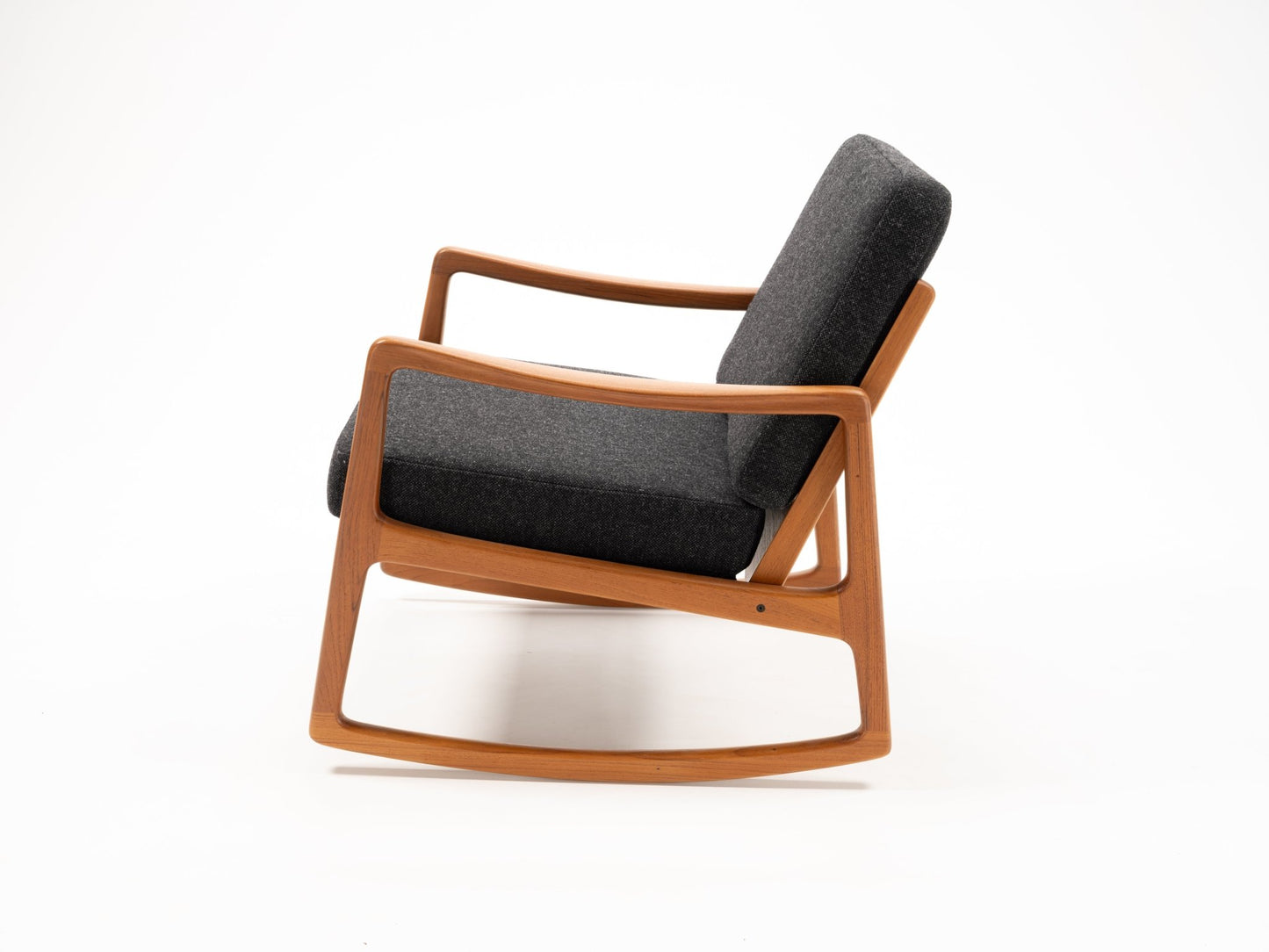Ole Wanscher rocking chair with sculpted teak frame and dark grey upholstered cushions in minimalist style