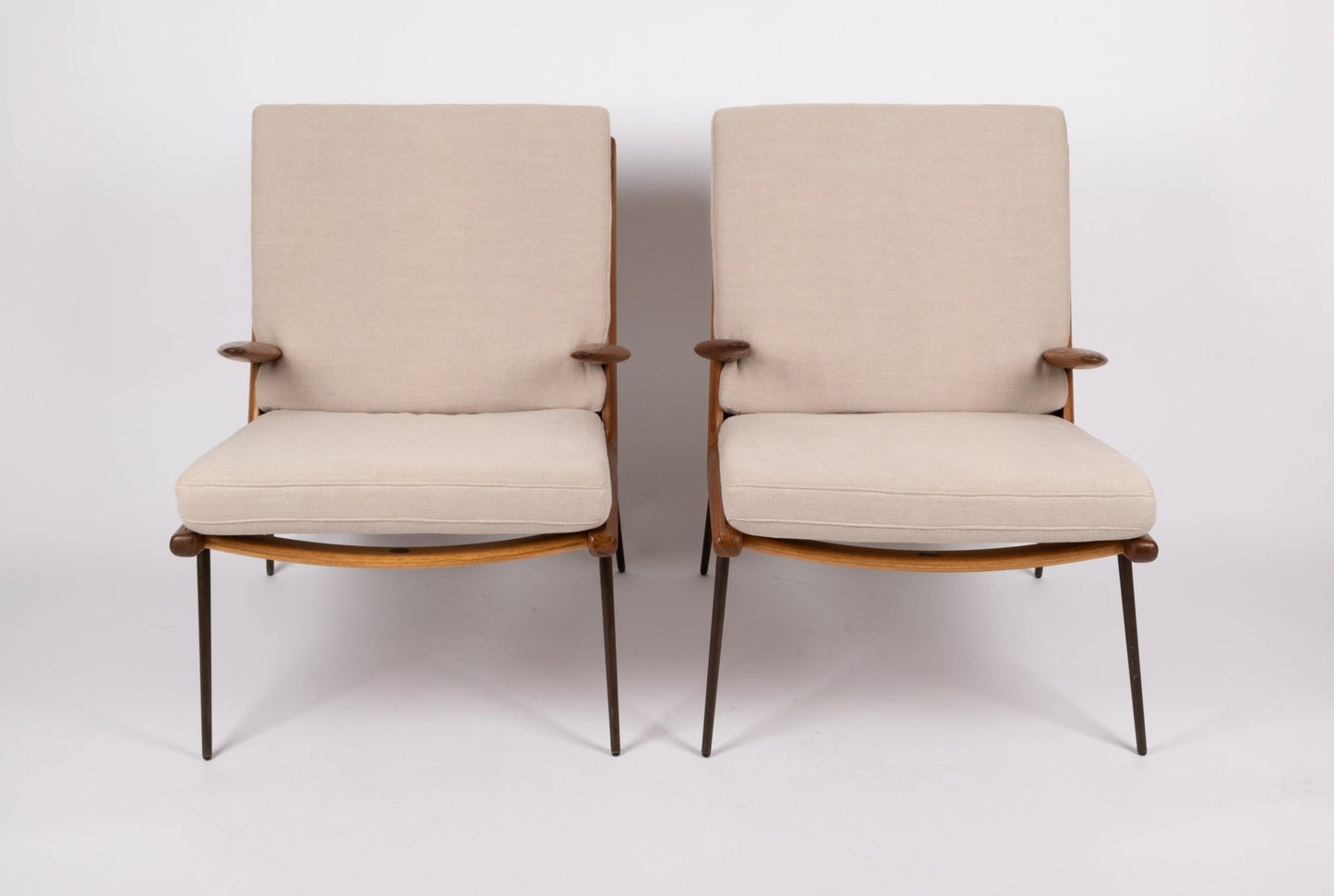 Pair of 1960s Peter Hvidt Boomerang lounge armchairs with teak frames, brass legs, and beige cushions on white background