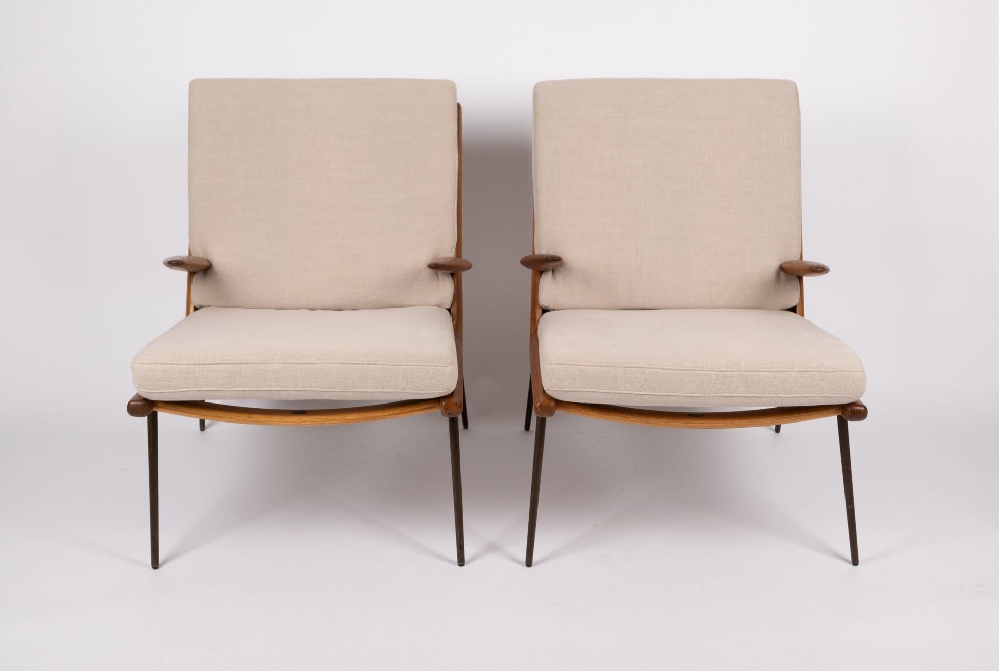 Pair of 1960s Peter Hvidt Boomerang lounge armchairs with teak frames, brass legs, and beige cushions on white background