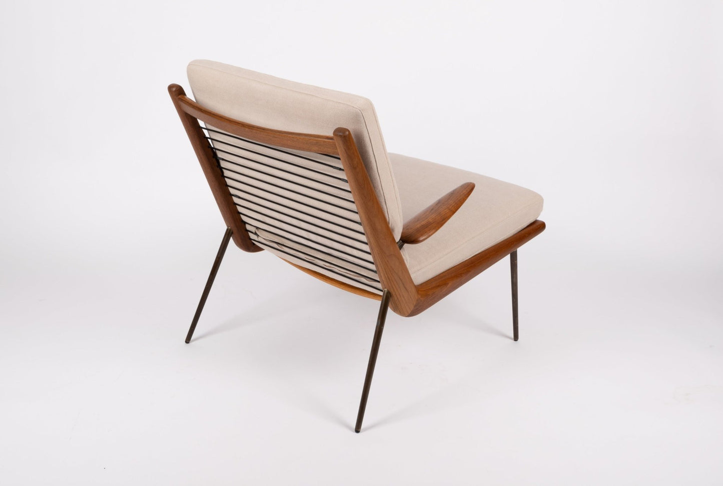 Mid-century modern Peter Hvidt Boomerang armchair with teak frame, brass legs, and beige cushioned seat on white background.