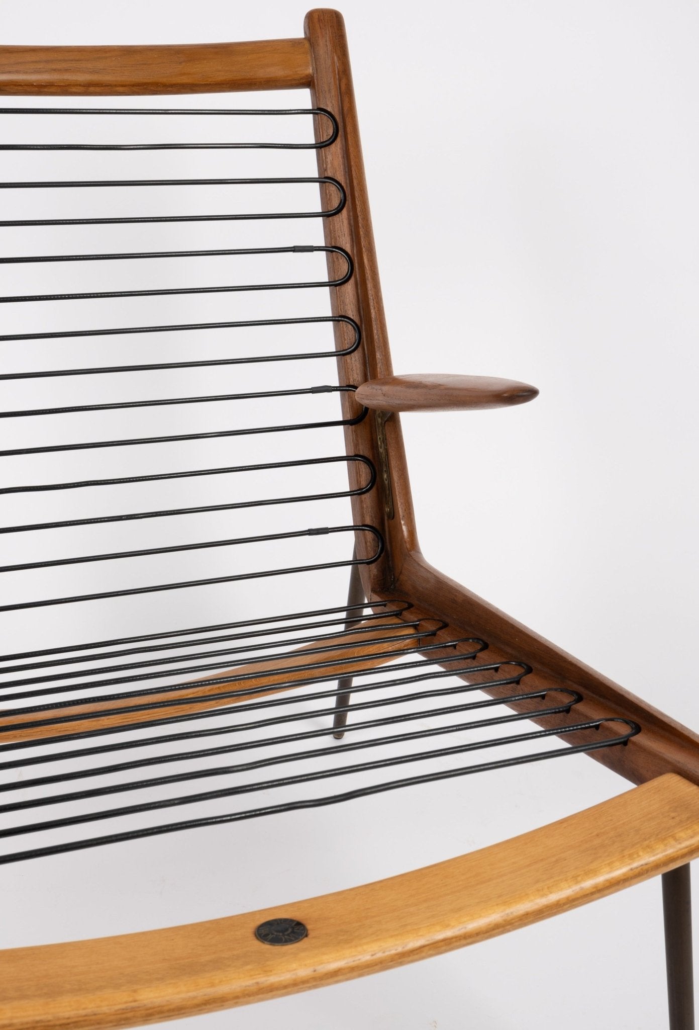 Close-up of Peter Hvidt Boomerang armchair with teak frame and black stretched cord seating on white background