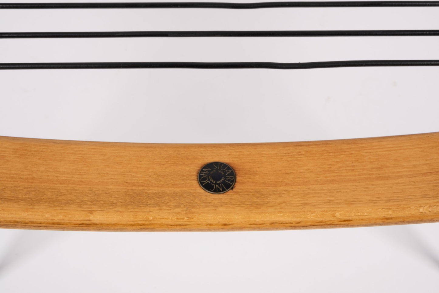 Close-up of teak wood boomerang chair frame with black France & Søn maker's mark medallion and brass legs detail