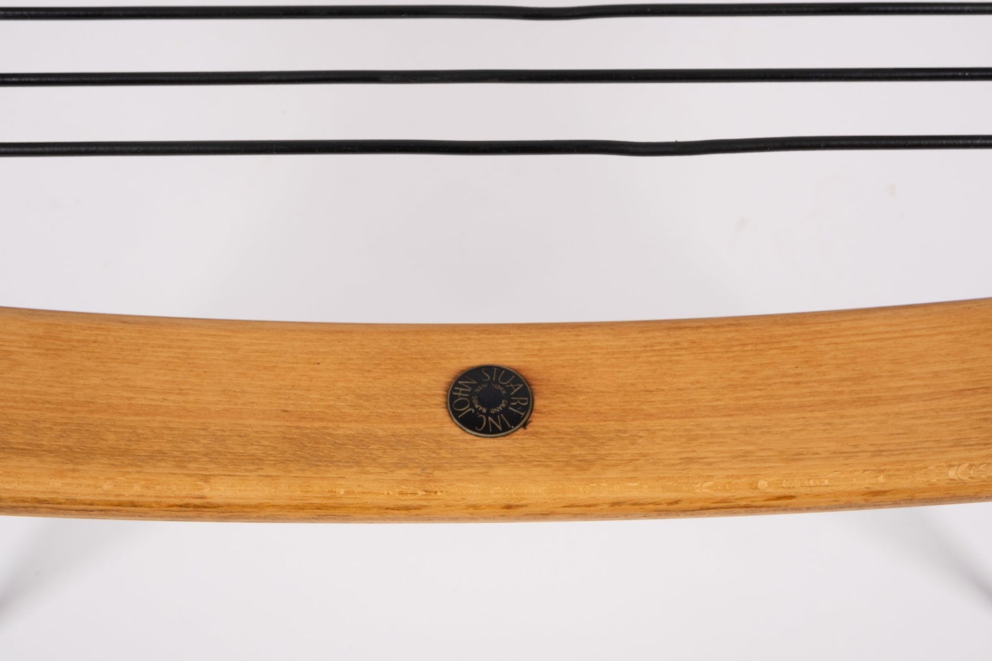 Close-up of teak wood boomerang chair frame with black France & Søn maker's mark medallion and brass legs detail