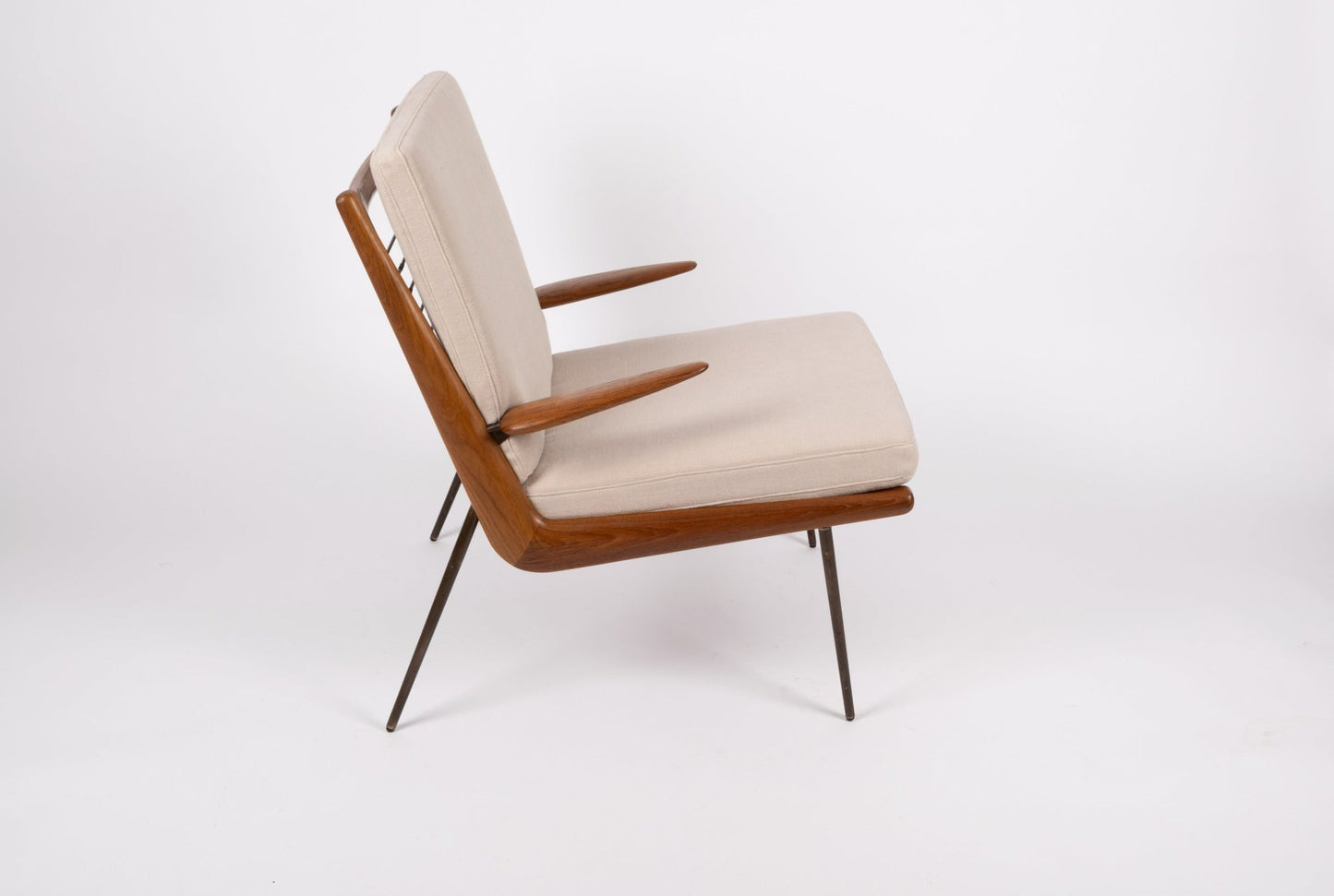 Mid-century modern Peter Hvidt "Boomerang" teak armchair with brass legs and light beige cushions on white background.