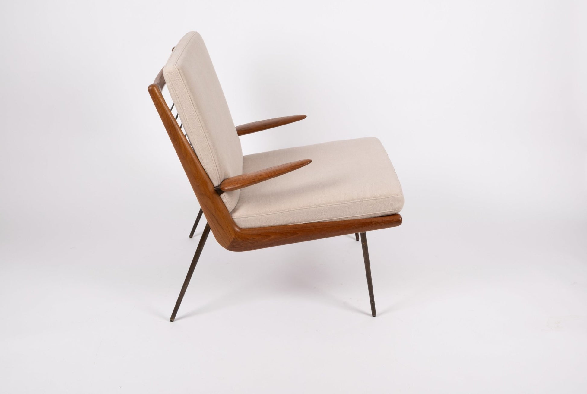 Mid-century modern Peter Hvidt "Boomerang" teak armchair with brass legs and light beige cushions on white background.