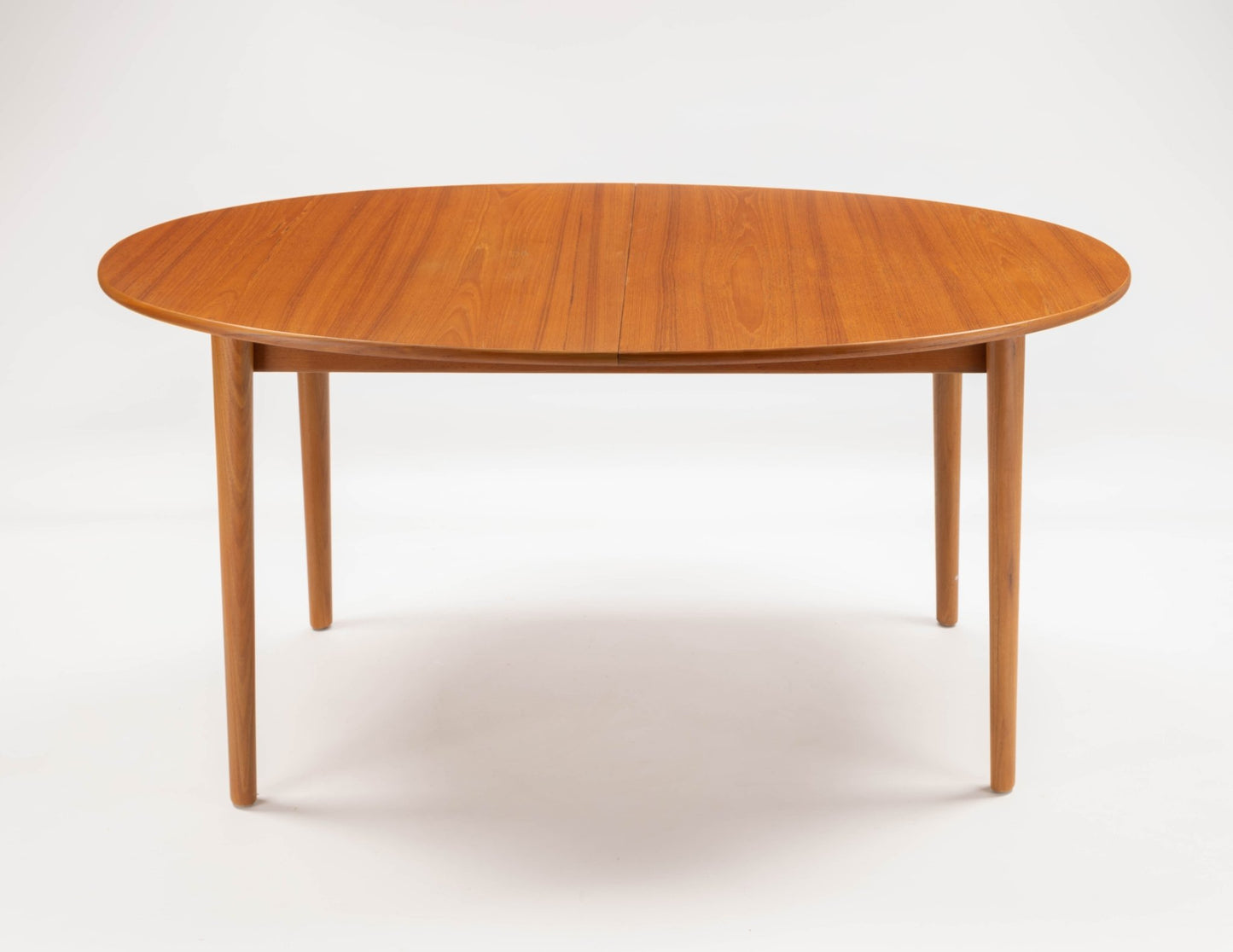 Peter Hvidt Model 311 extendable teak dining table with round top and tapered turned legs on white background