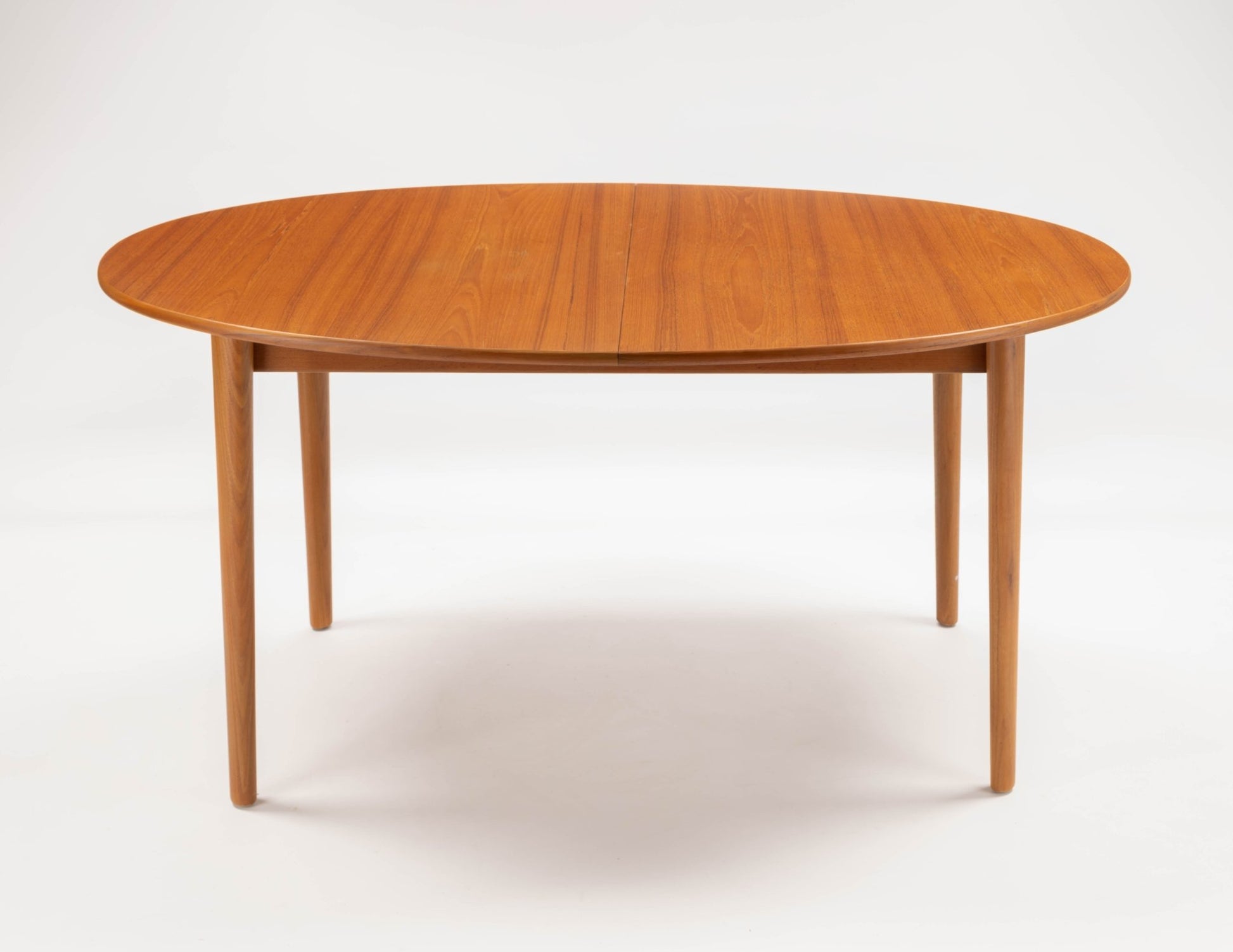 Peter Hvidt Model 311 extendable teak dining table with round top and tapered turned legs on white background