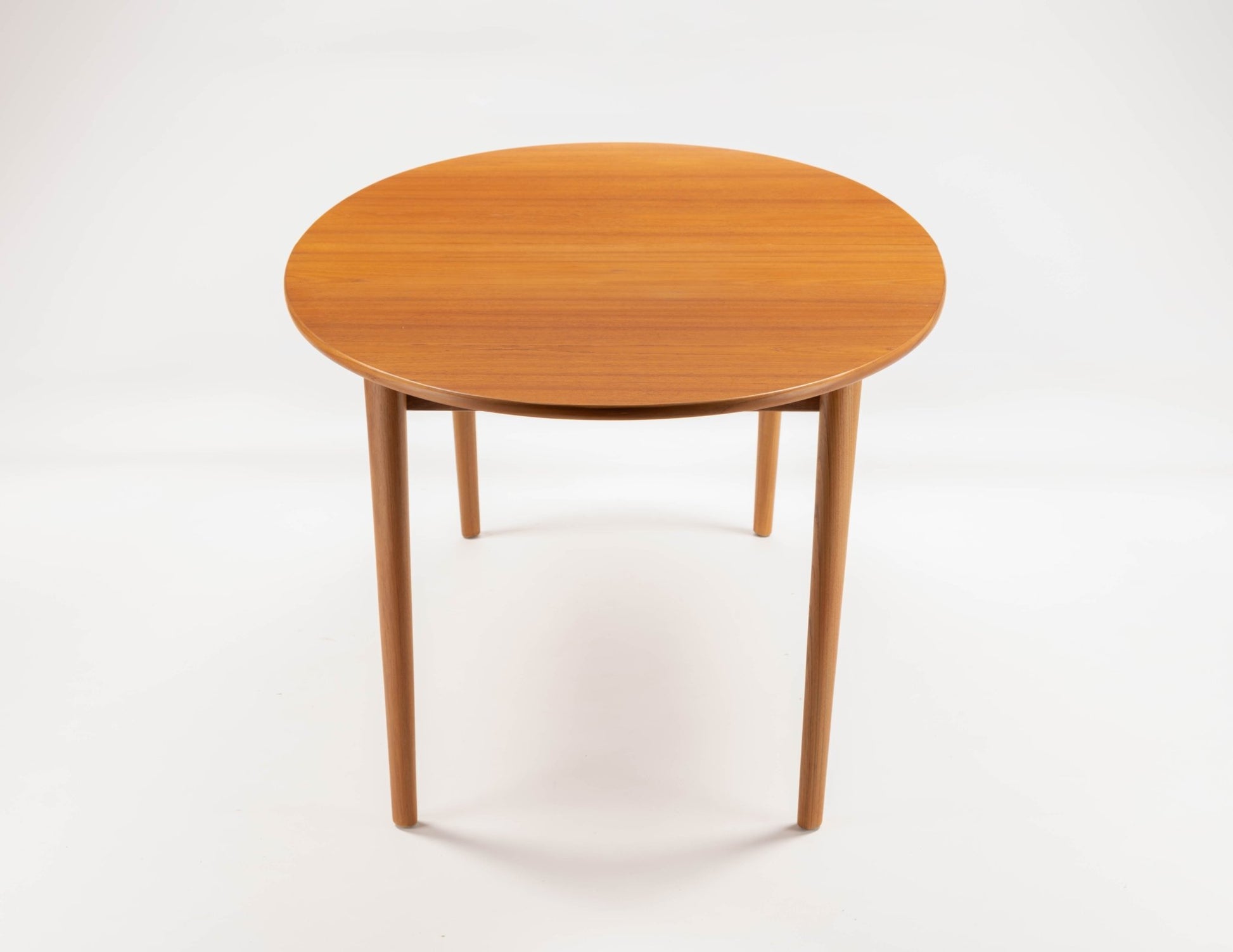 Peter Hvidt Model 311 mid-century modern round teak dining table with tapered turned legs on white background