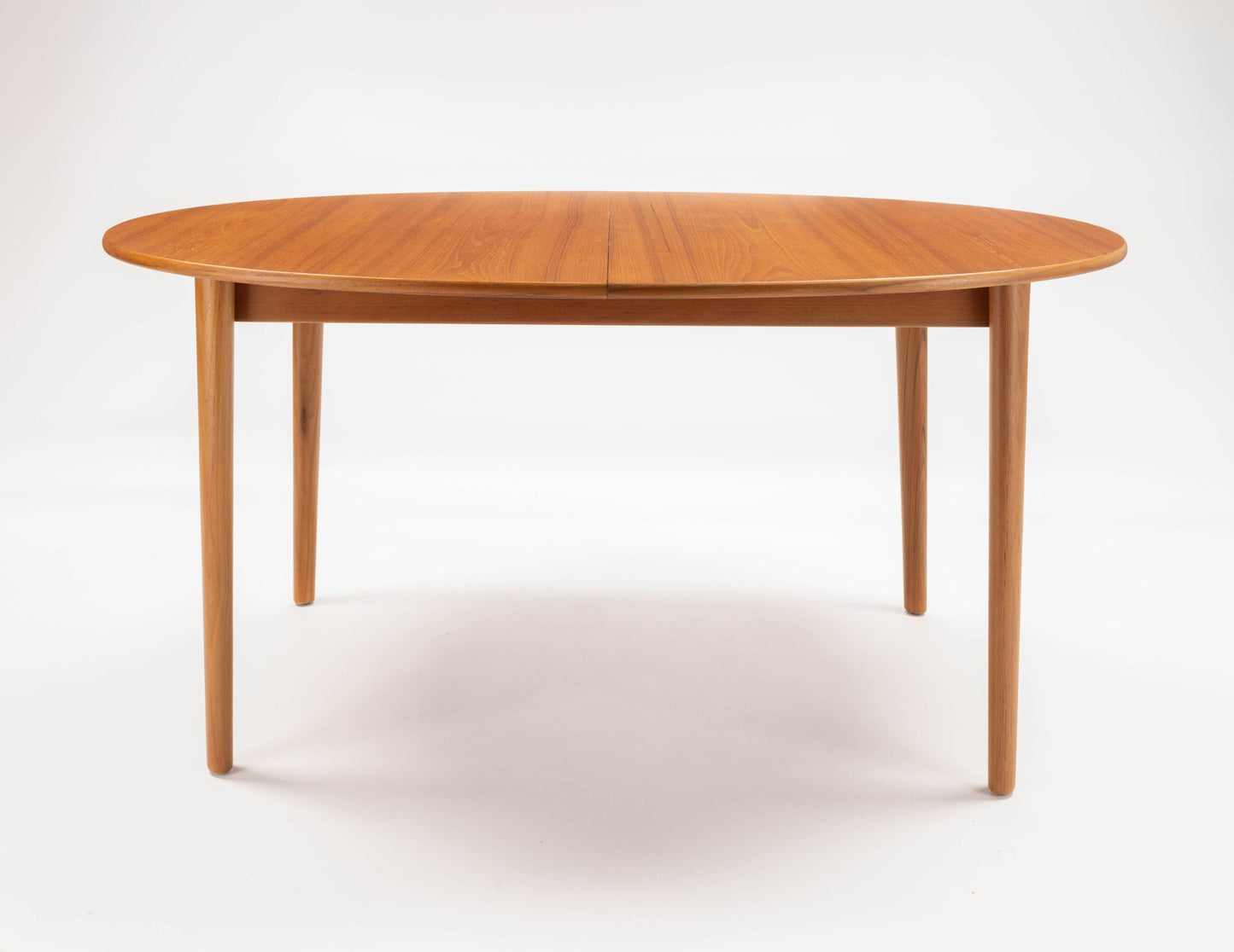 Peter Hvidt Model 311 extendable teak dining table with round top and tapered turned legs on white background