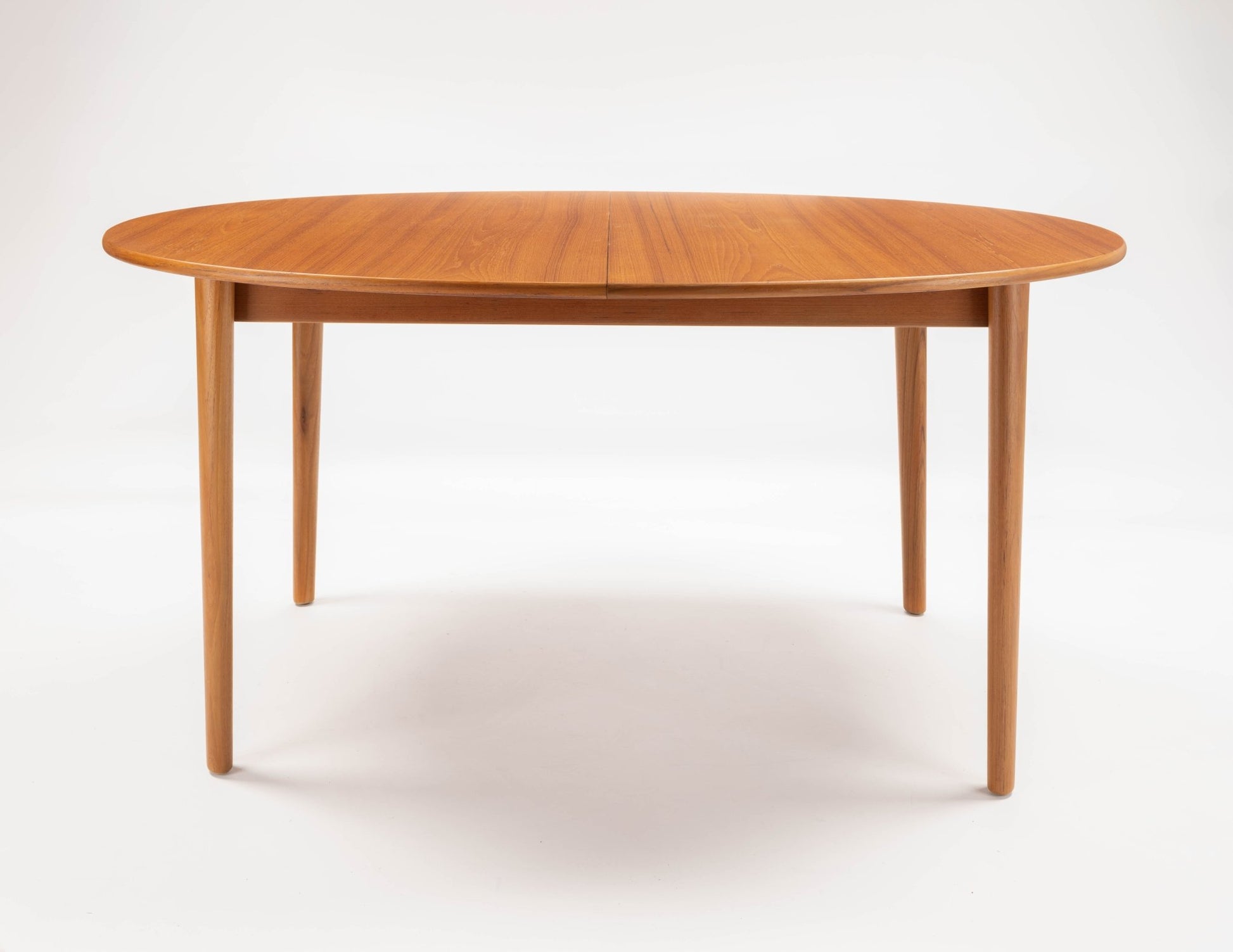 Peter Hvidt Model 311 extendable teak dining table with round top and tapered turned legs on white background