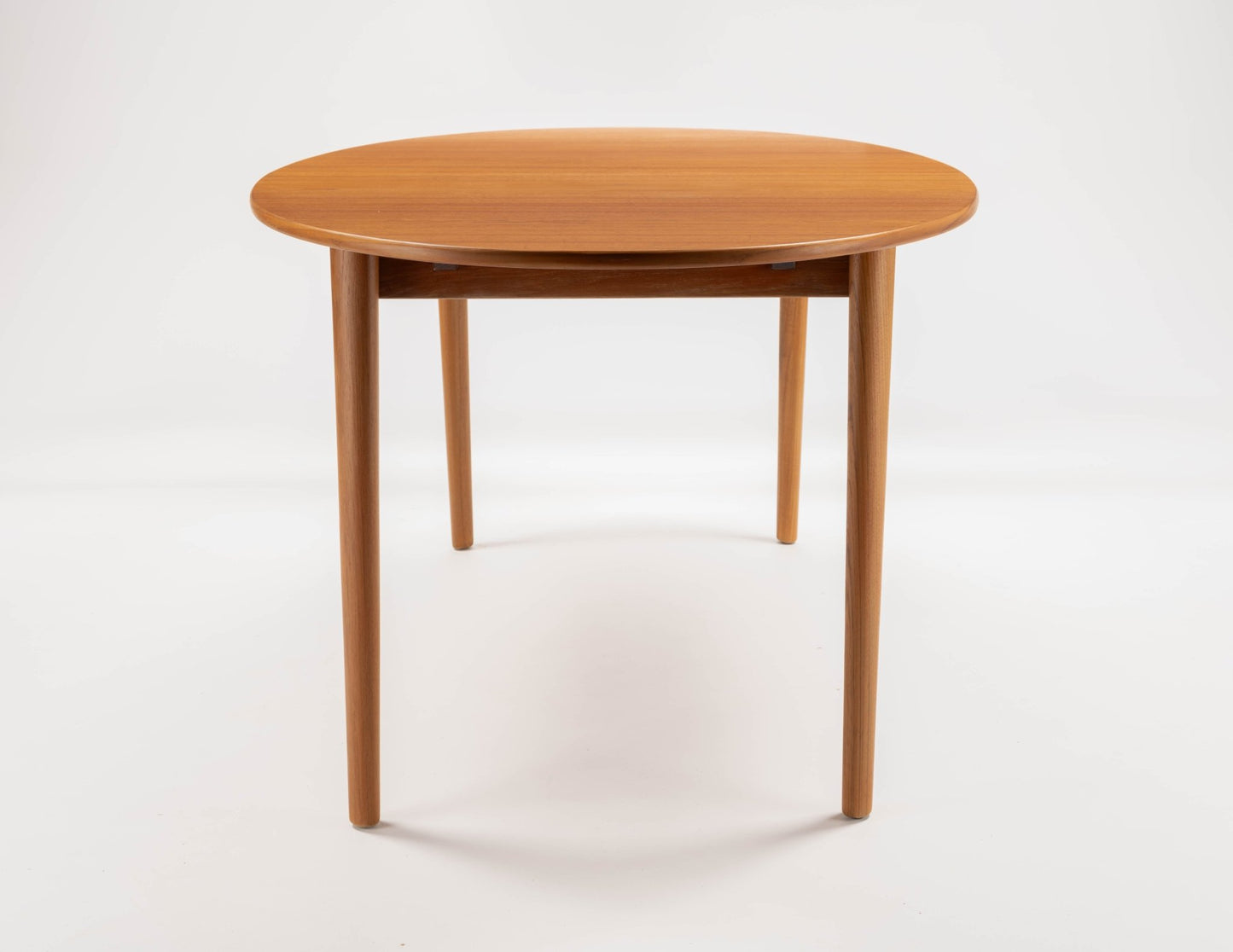 Peter Hvidt Model 311 extendable round teak dining table with tapered turned legs on white background