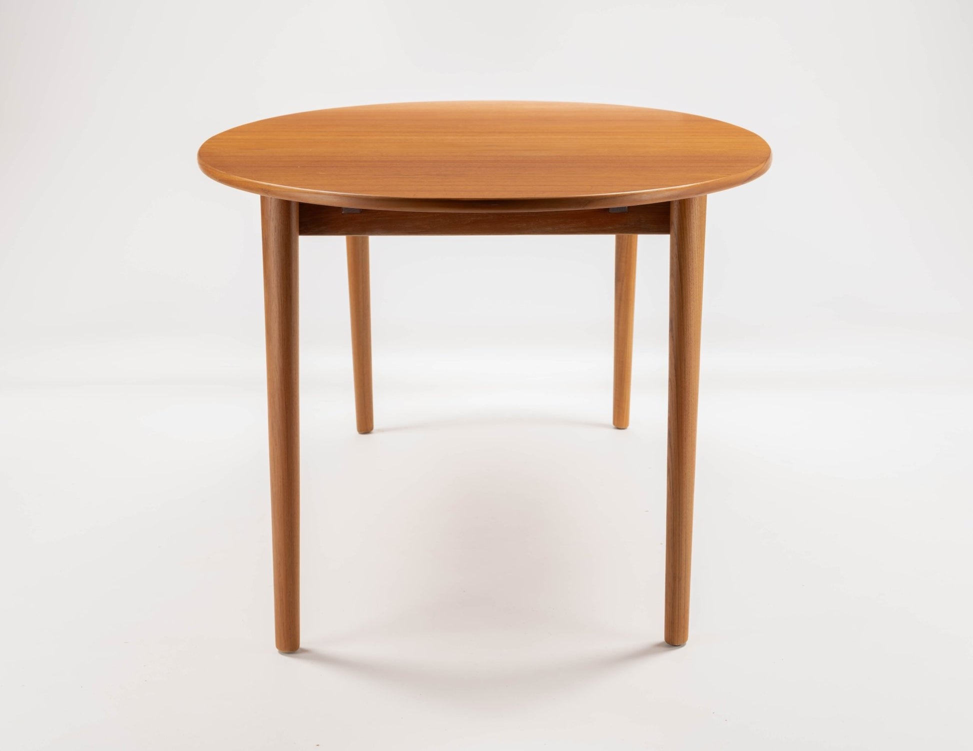 Peter Hvidt Model 311 extendable round teak dining table with tapered turned legs on white background