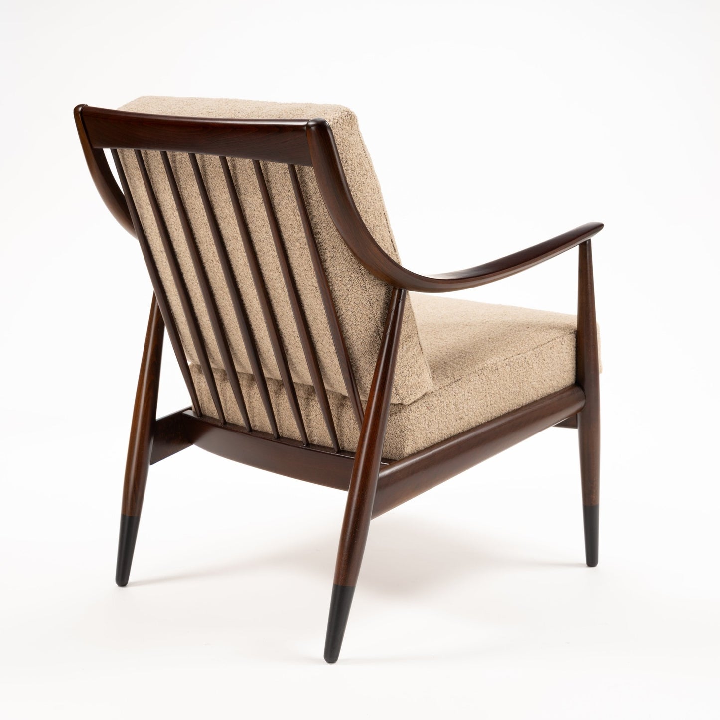 Peter Hvidt Model FD 145 Lounge Chair viewed from the rear with dark wood frame vertical spindles beige upholstery and tapered legs in vintage Danish furniture style