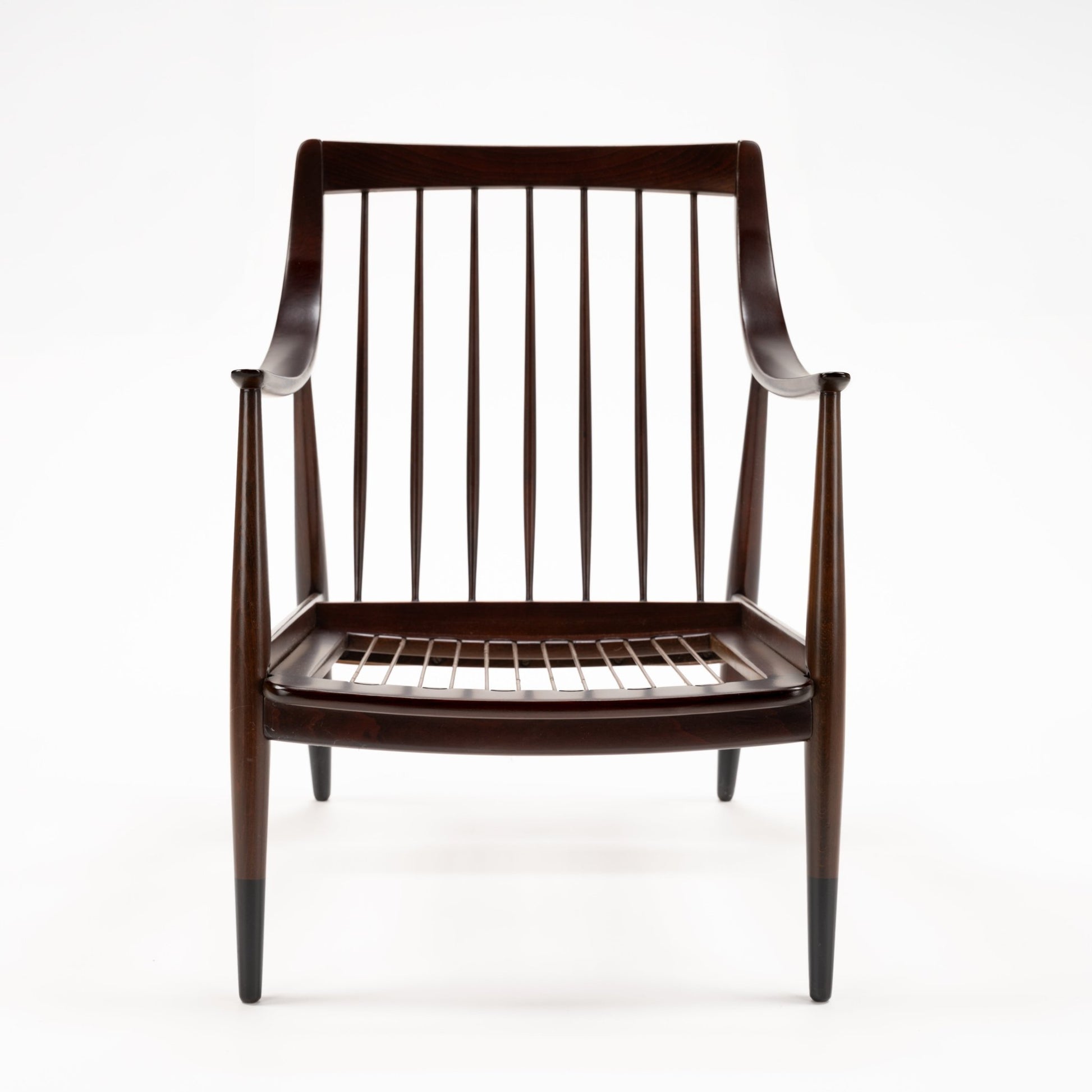 Peter Hvidt Model FD 145 Lounge Chair with dark sculpted wood frame curved arms spindle back and exposed seat springs in vintage Danish furniture style